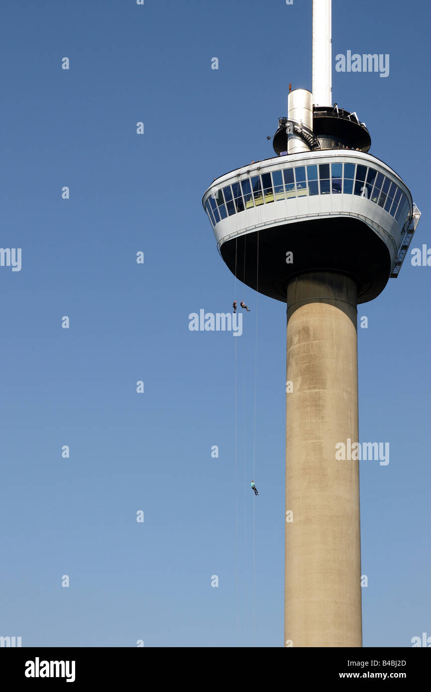 Tre uomini persone appendere arrampicata corda linea torre di cemento Euromast mast blue sky sport ad alta altitudine pericolo divertimento Rotterdam Foto Stock