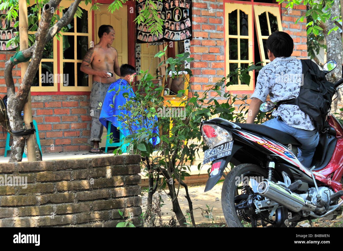 Ragazzo Balinese è in attesa di un suo amico per terminare il taglio di capelli fatto,Bali, Indonesia Foto Stock