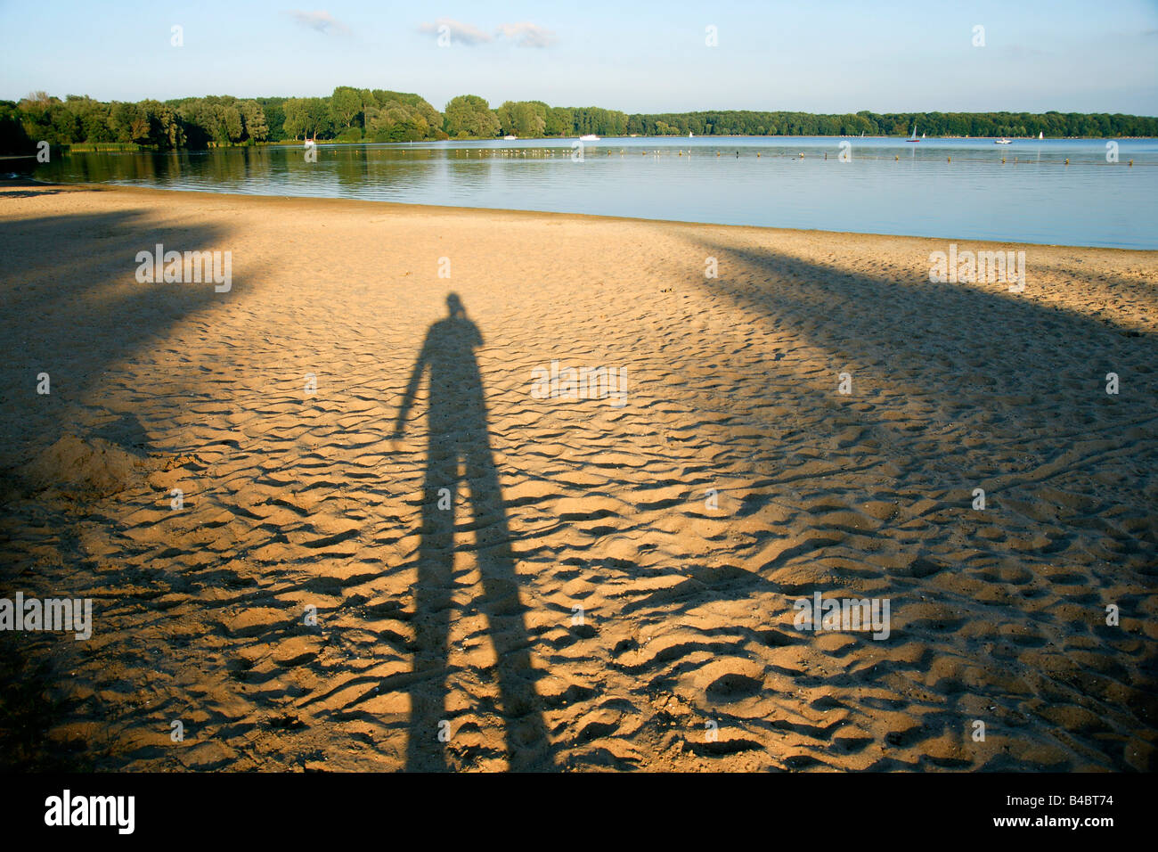 Uomo Ombra spiaggia di sabbia a riva lago lato luce tenue sera Kralingse lago di Rotterdam Paesi Bassi Foto Stock