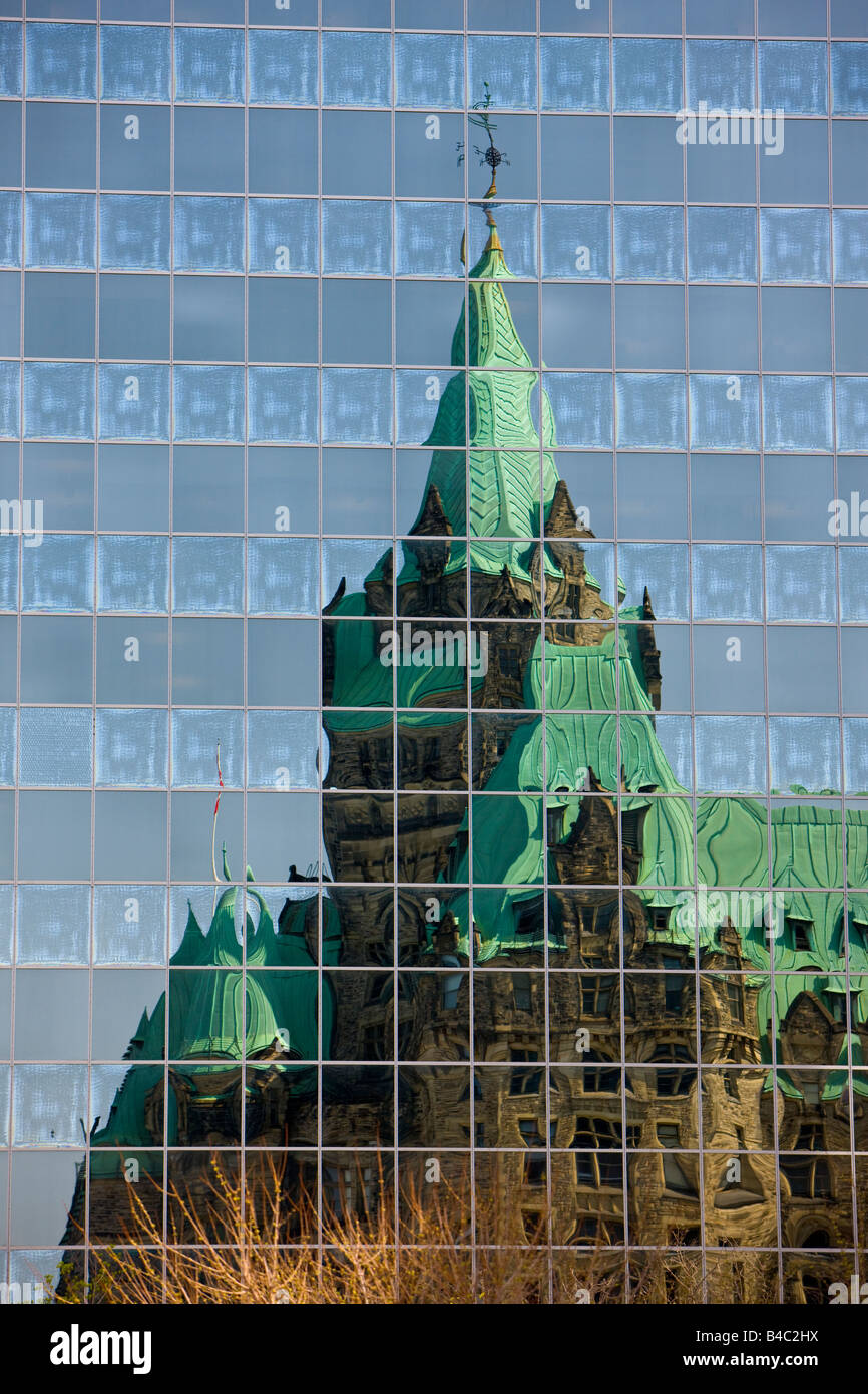 Le riflessioni della Confederazione edificio nelle finestre di un edificio moderno nella città di Ottawa, Ontario, Canada. Foto Stock