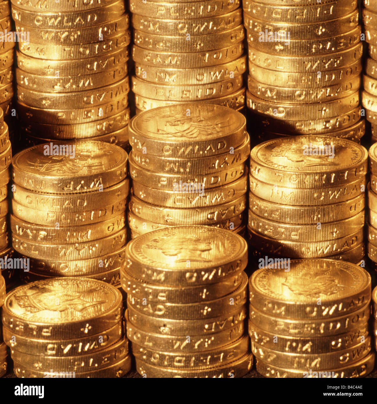 Close up di pile di denaro del Regno Unito una sterlina monete in contanti sotto illuminazione oro Concetto di immagine per nido uovo pila di risparmio di denaro di pile di denaro Foto Stock
