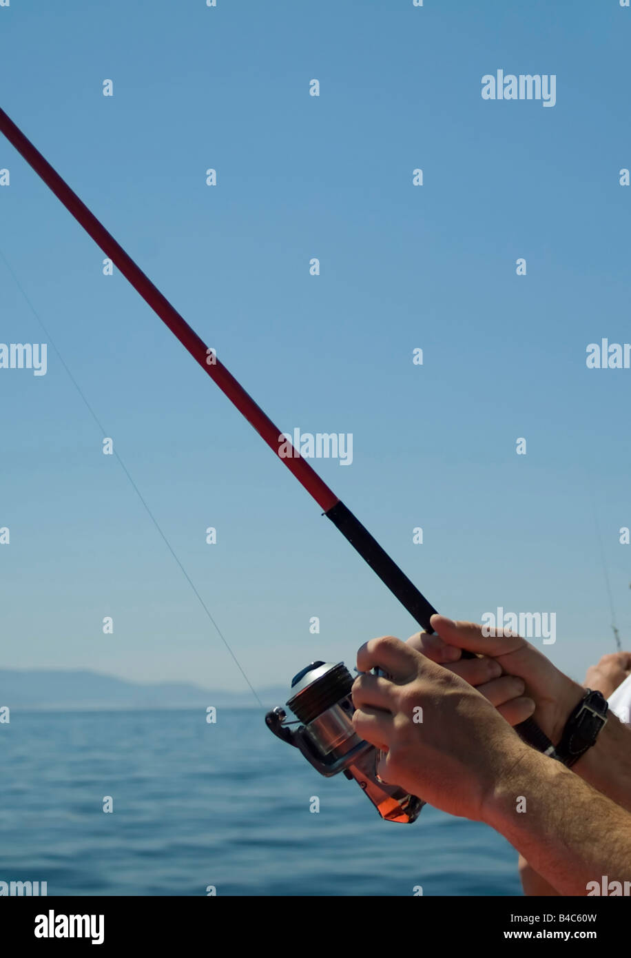 Un uomo di pesca a mosca in mare in una giornata di sole Foto Stock