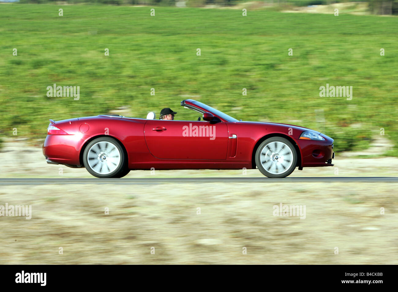 Jaguar XK 4.2 V8 Cabrio, modello anno 2006-, rosso, guida, vista laterale, country road, geöffnetes / Verdeck openes Foto Stock