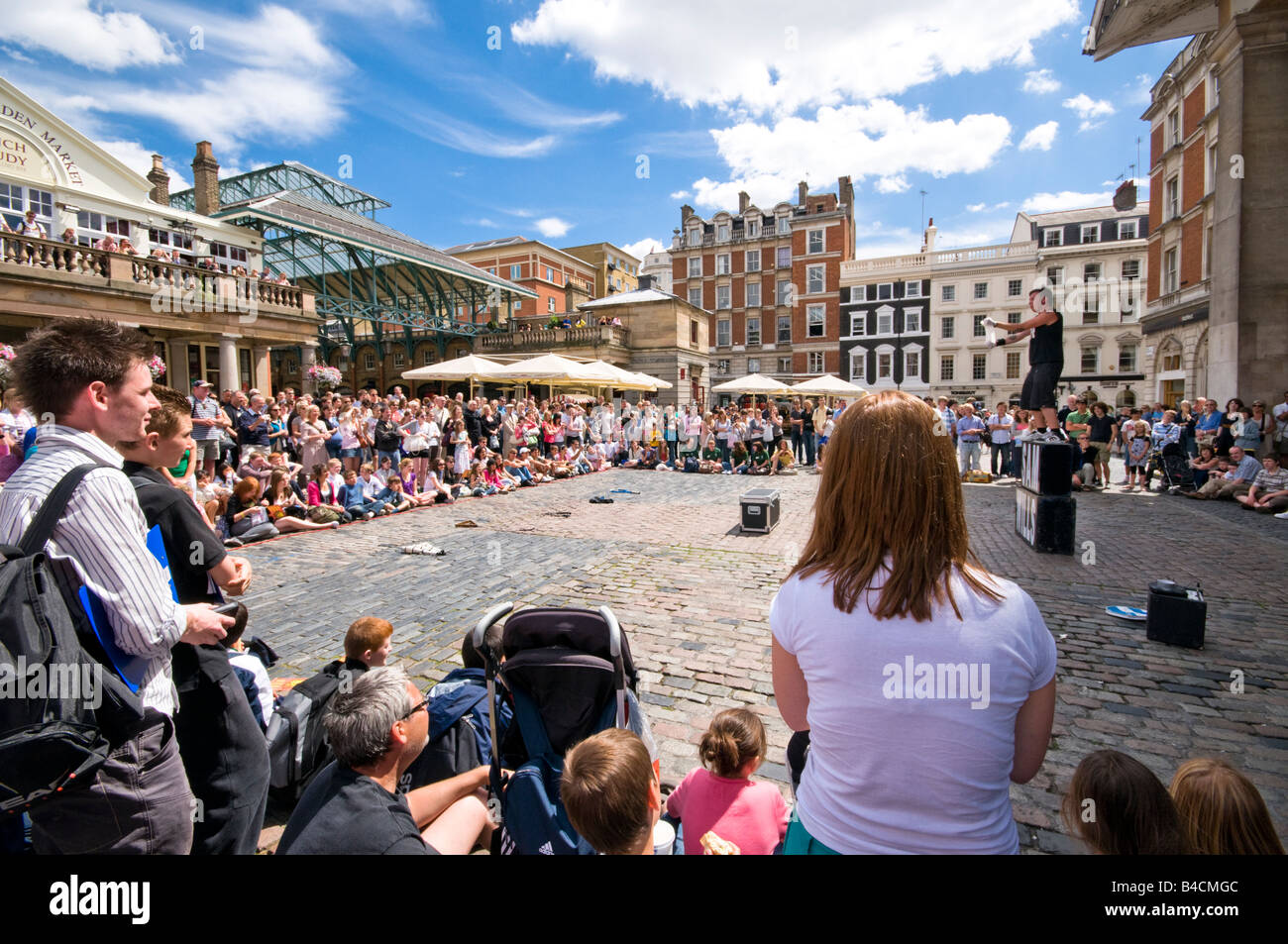 Guardare la gente una strada intrattenitore musicista di strada, Covent Garden di Londra, Regno Unito Foto Stock