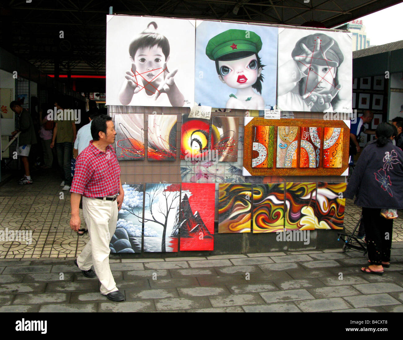 Un uomo cammina passato Arte in vendita Panjiayuan Mercato delle Pulci a Pechino, Cina Foto Stock