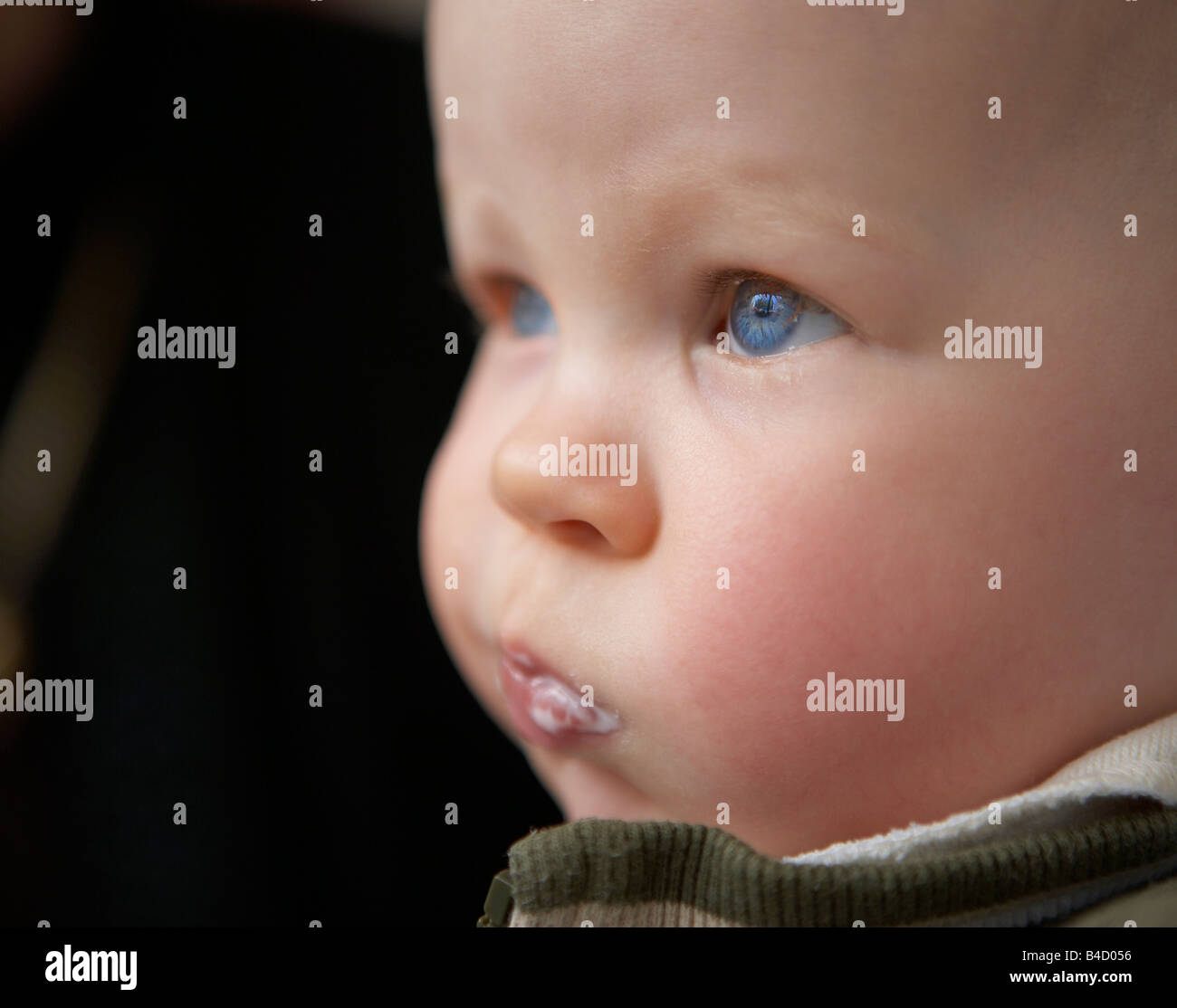 Baby Boy con gli occhi blu e il latte sulla bocca Foto Stock