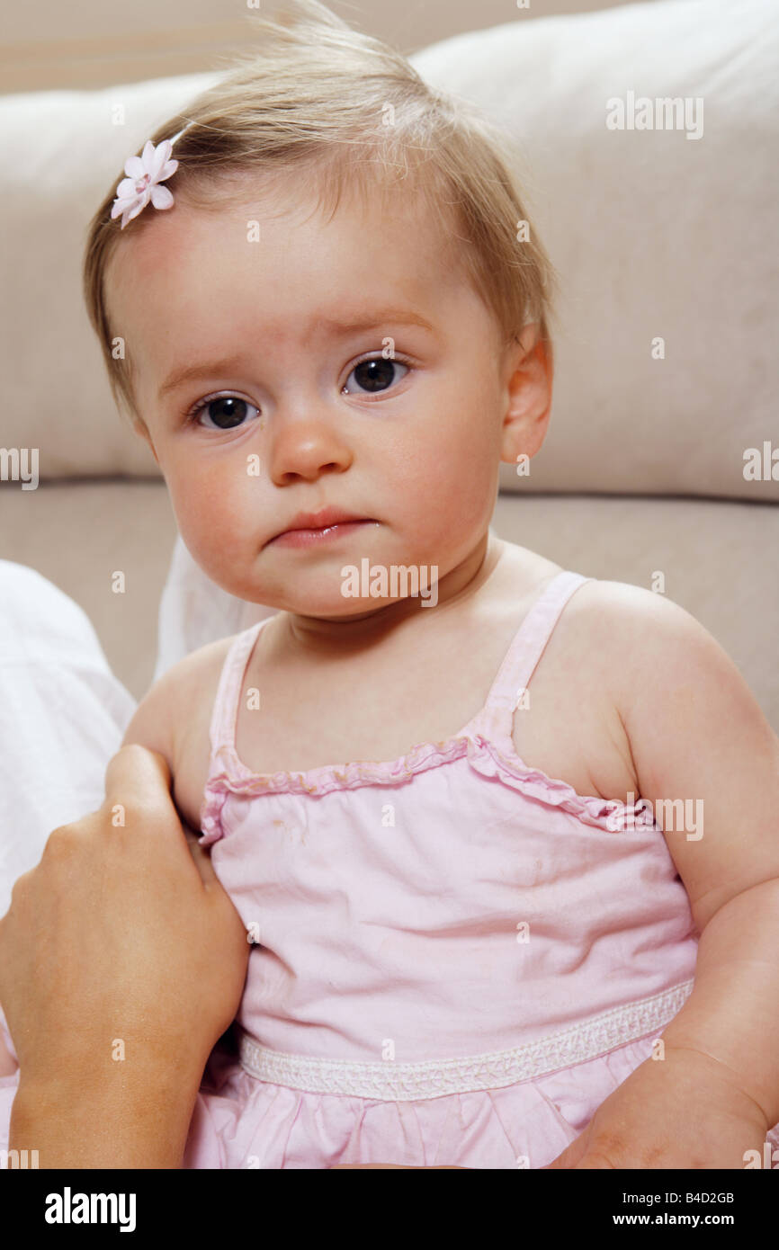 A nove mesi di età ragazza seduta verso il basso con una faccina triste Foto Stock