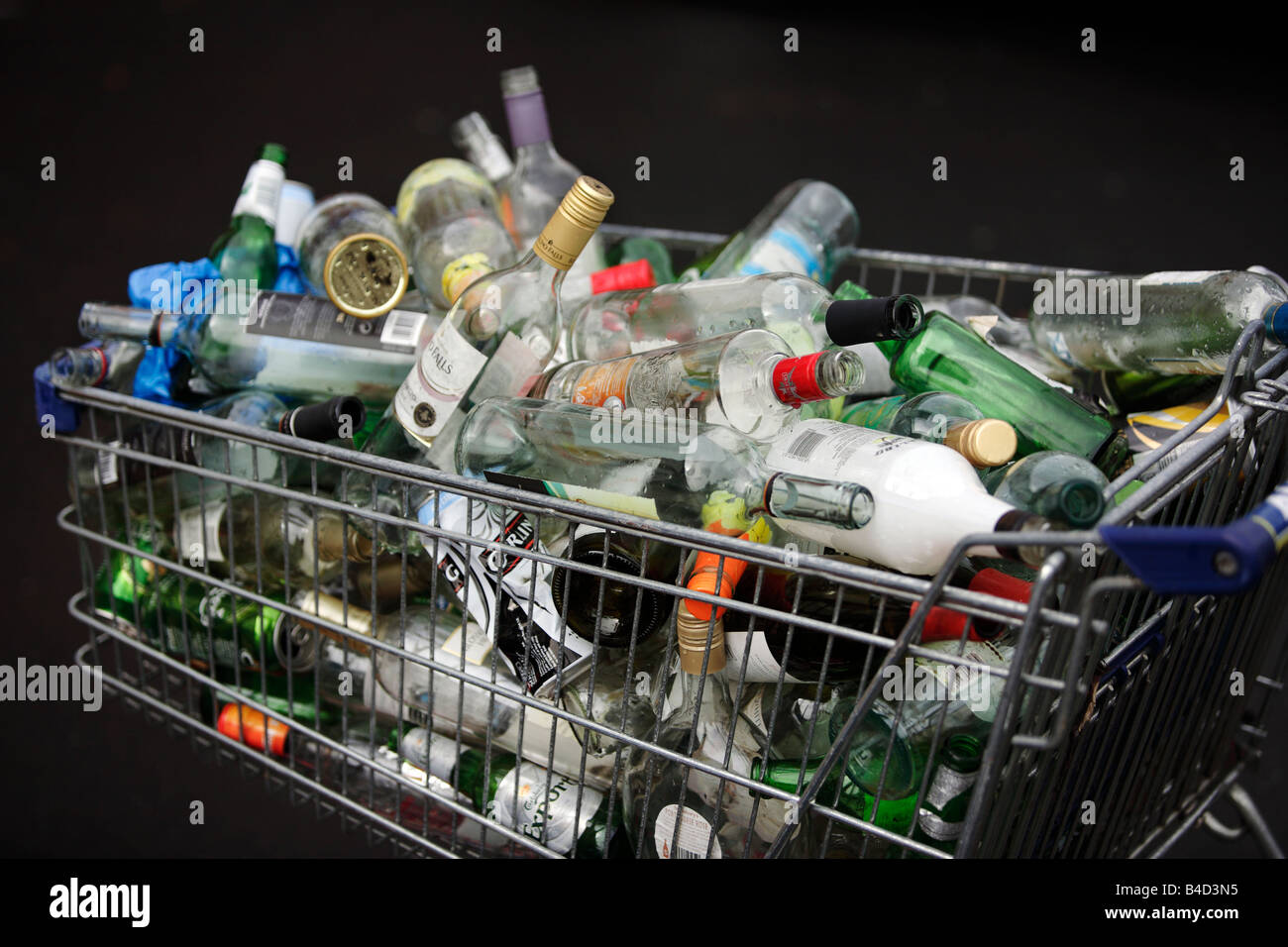 Un carrello per supermercati piena di svuotare le bottiglie e lattine in attesa di raccolta sul marciapiede fuori da un piatto in Birmingham. Foto Stock