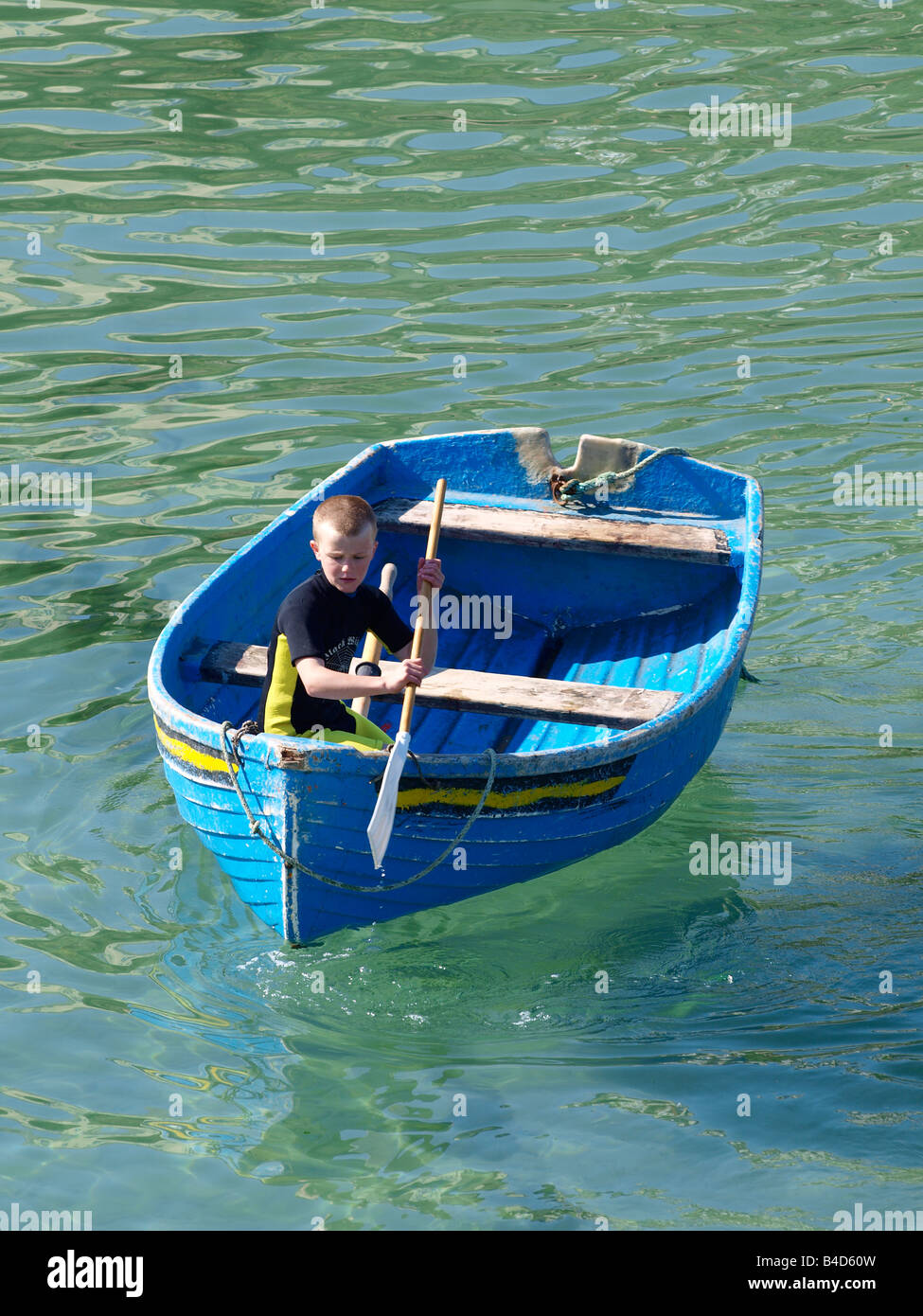 Ragazzo che indossa una muta shortie in una barca a remi Foto Stock