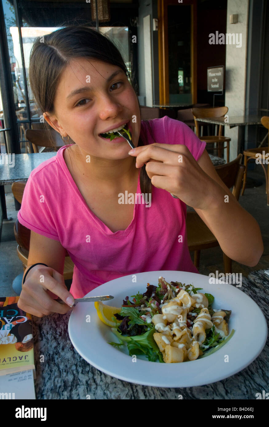 Giovane ragazza adolescente che mangia una sana insalata di calamari di sale e pepe in un ristorante Foto Stock