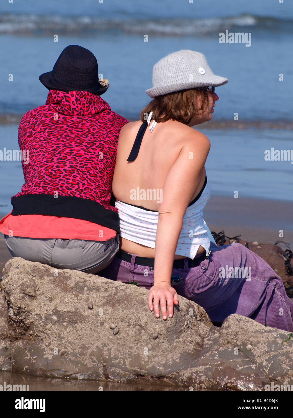 Due giovani donne sedeva su una roccia in spiaggia Foto Stock