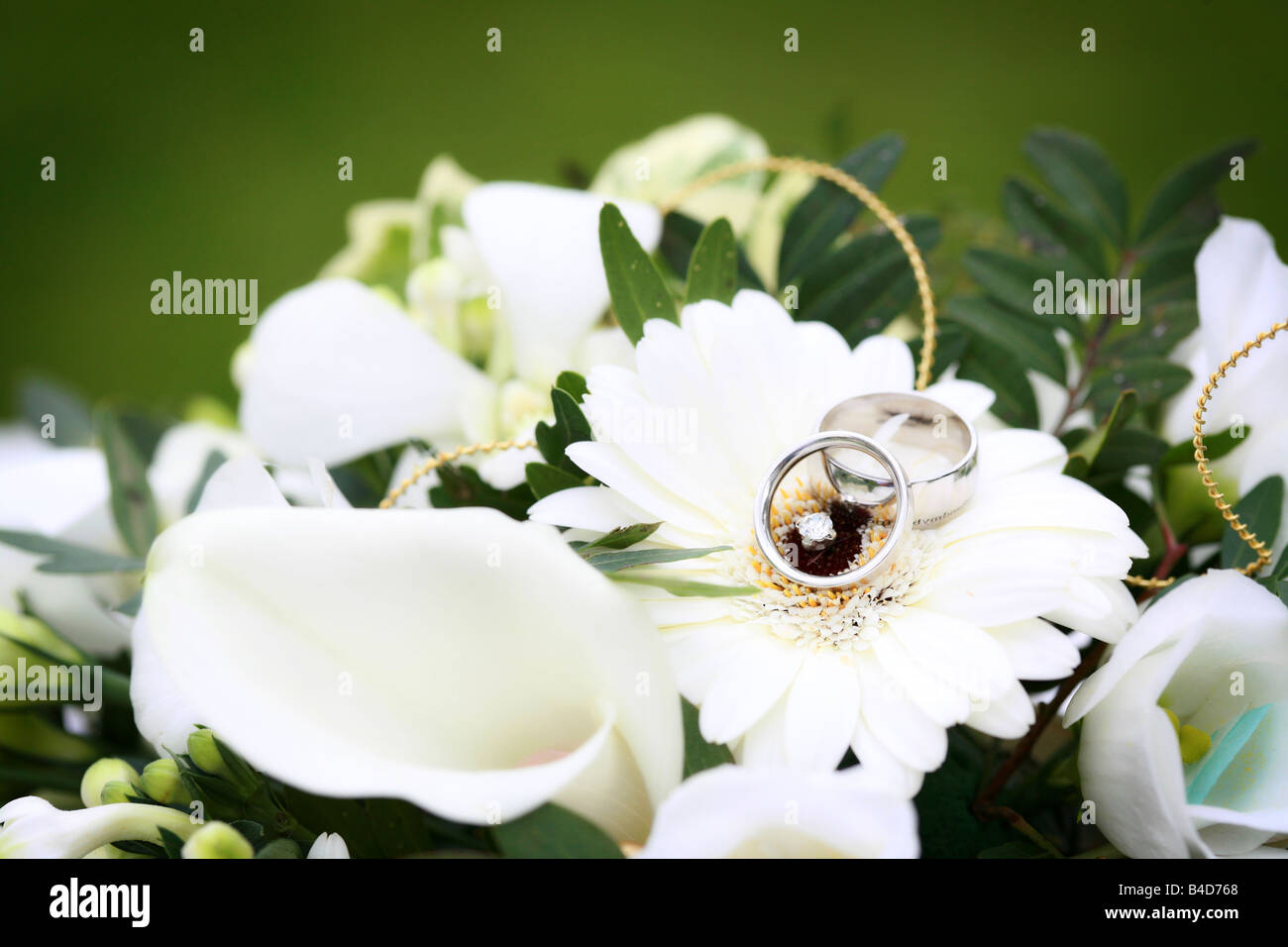Bianco Argento Oro Platino fedi bande in appoggio sul fiore bianco nel bouquet nuziale generic felice giorno di nozze immagine Foto Stock