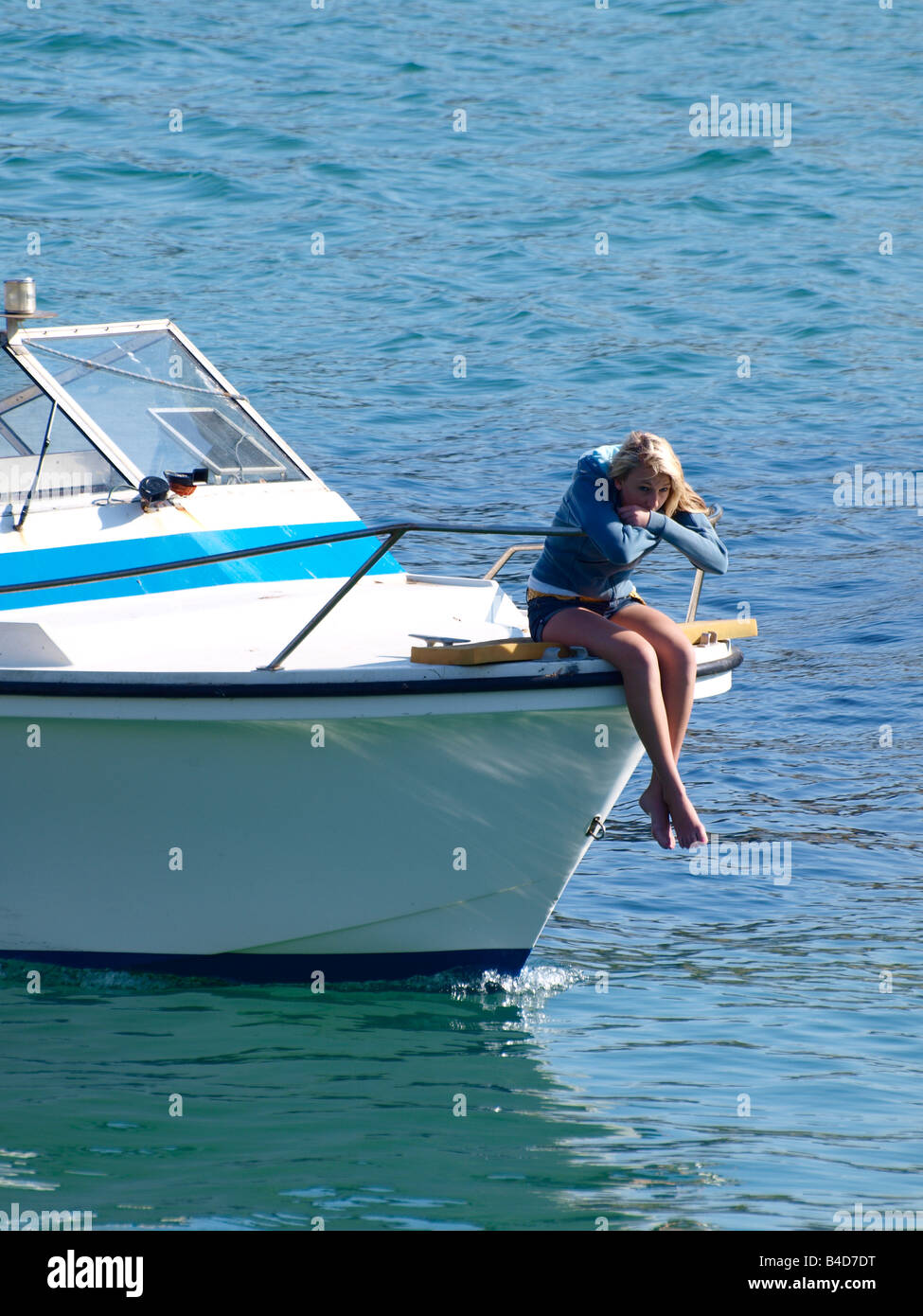 Giovane donna sedeva sulla prua di una barca Foto Stock