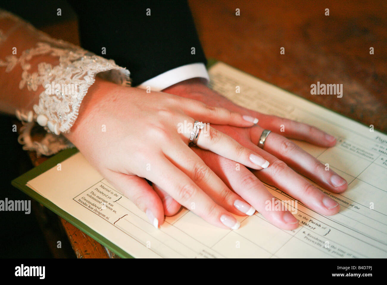 Sposi ha sposato il marito e la moglie tenendo le mani sul registro di matrimonio durante la cerimonia di matrimonio nel Regno Unito Foto Stock