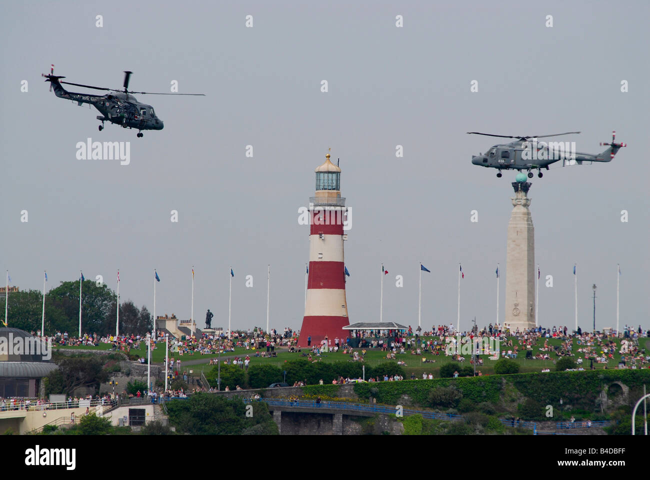 Due Royal Navy elicotteri sopra Smeaton's Tower (faro) su Plymouth Hoe, UK, con la folla di persone (2008 Transat Race) Foto Stock