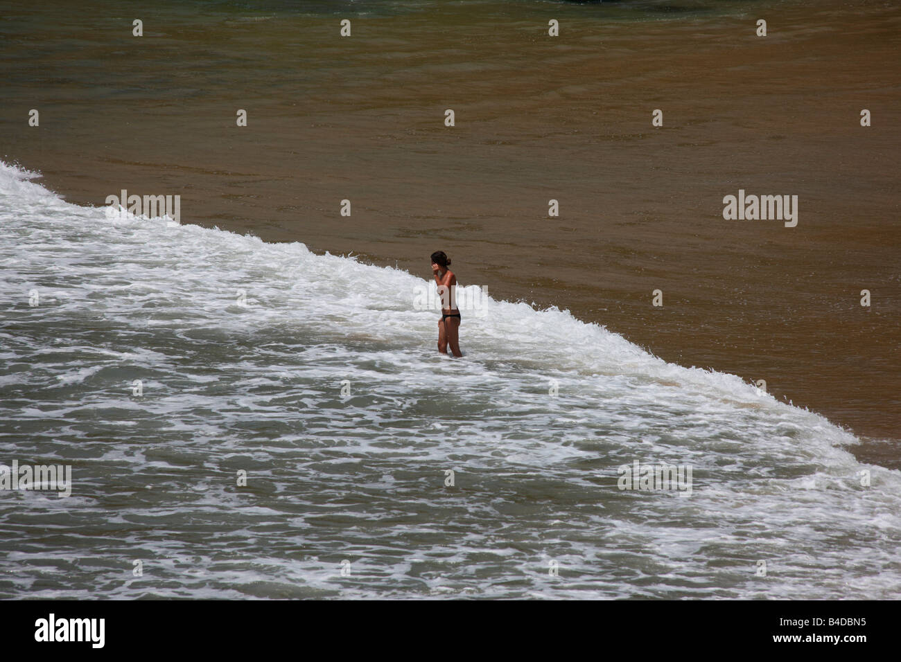 Una donna su una spiaggia godendosi la spuma del mare Foto Stock