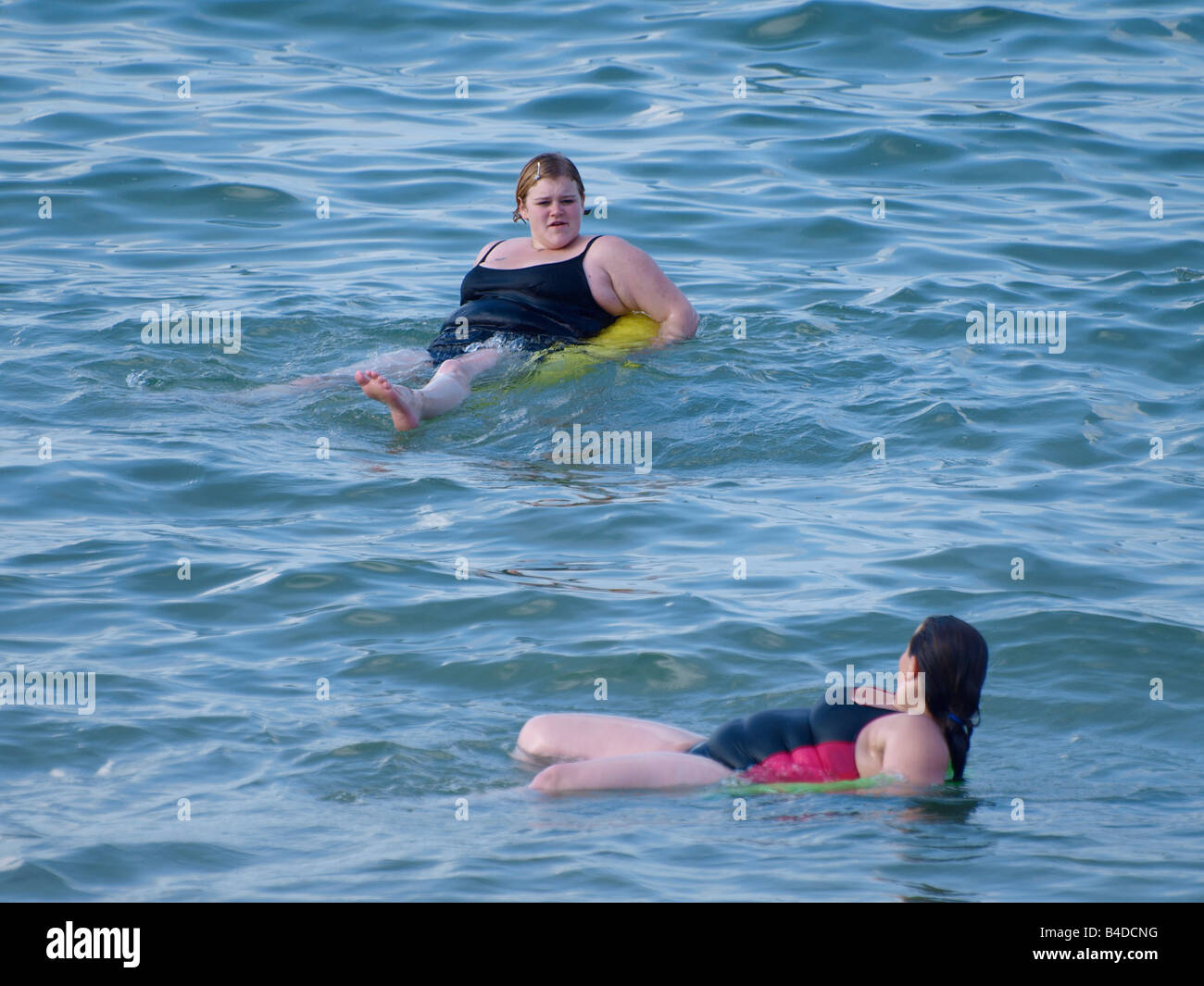 Due donne obese su anelli di gomma in mare Foto Stock