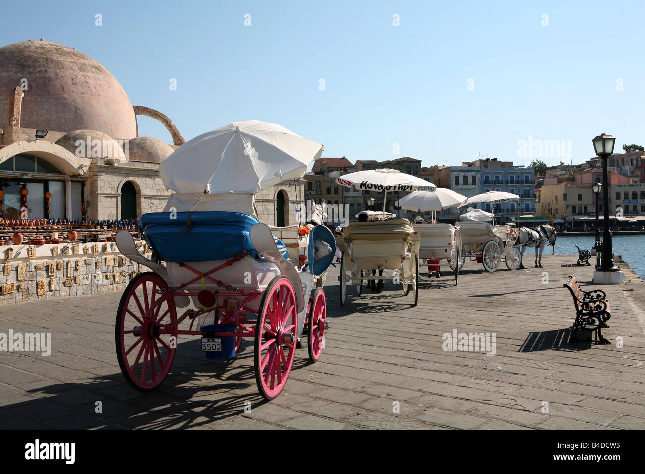 Una linea di cavallo e i taxi di fronte al porto a Hania Creta accanto alla moschea di Janissaries Foto Stock