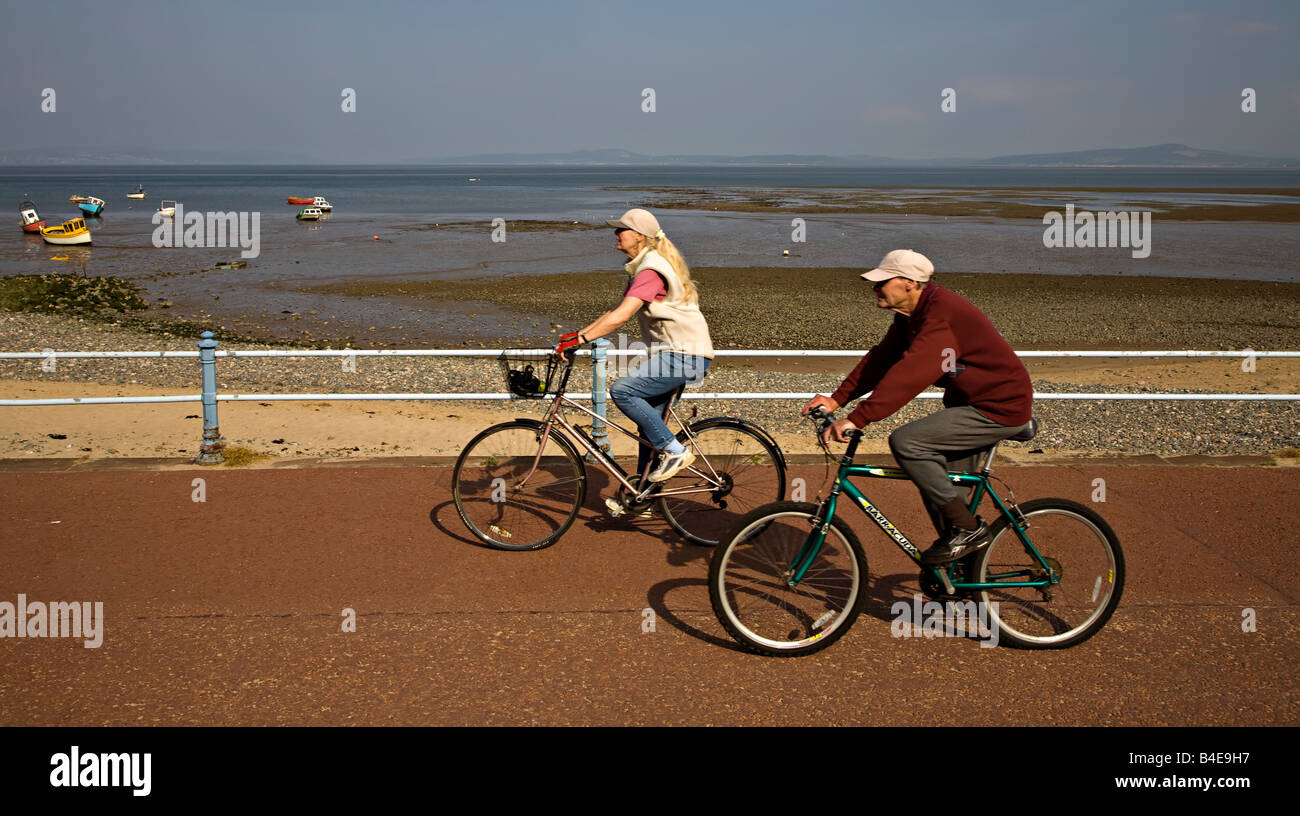 Due persone in bicicletta passeggiate sul lungomare di Morecambe Inghilterra LANCASHIRE REGNO UNITO Foto Stock