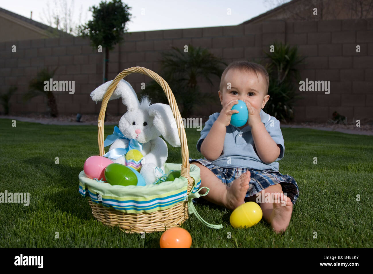 Un simpatico playfull 1 anno vecchio ragazzo giocando con le uova di pasqua dalla sua pasqua con cestello Foto Stock