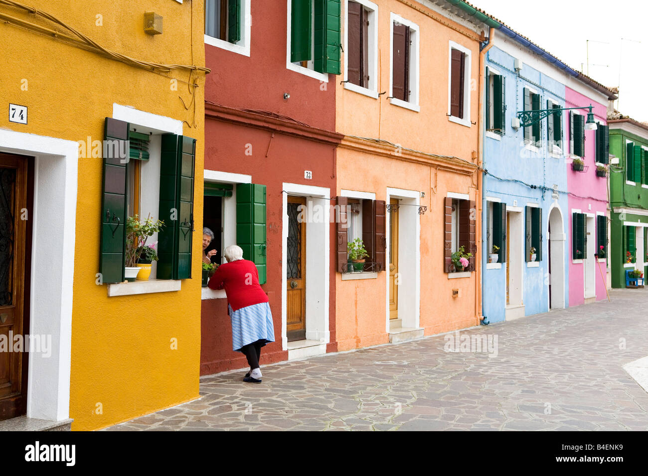 Conversazione tra due donne al di fuori di case variopinte di Isola di Burano Venezia Italia Foto Stock