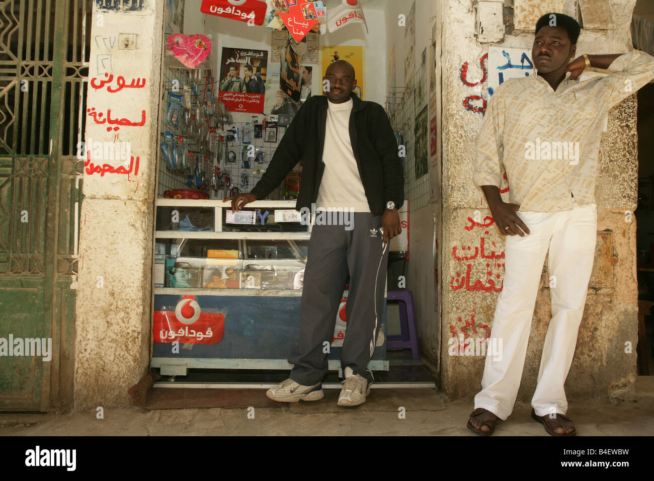 Un rifugiato sudanese di fronte al suo mobilephone accessori e officina di riparazione del Cairo in Egitto. Foto Stock