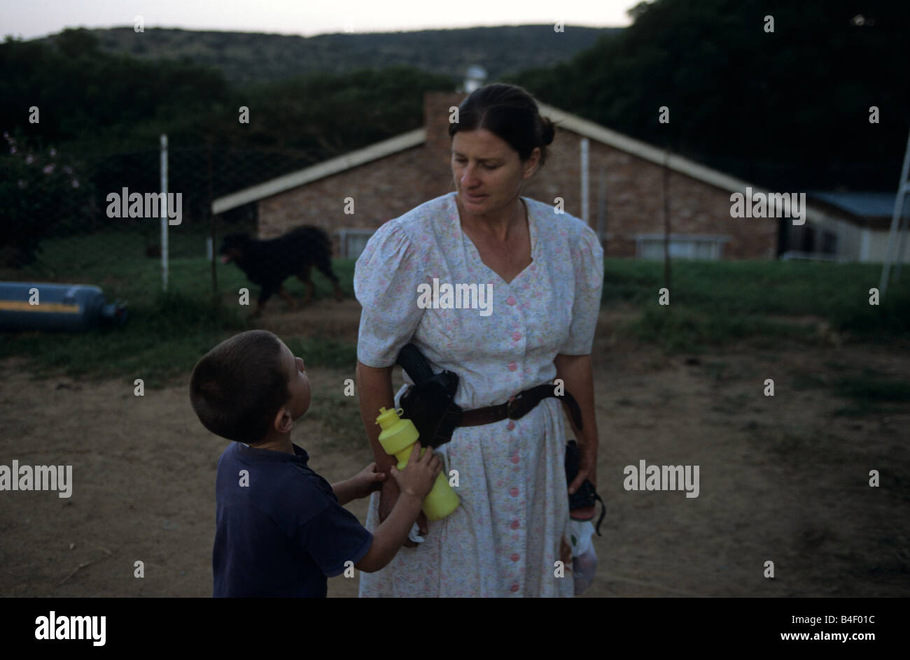 La donna caucasica portando la pistola a parlare con il figlio in fattoria, Sud Africa Foto Stock