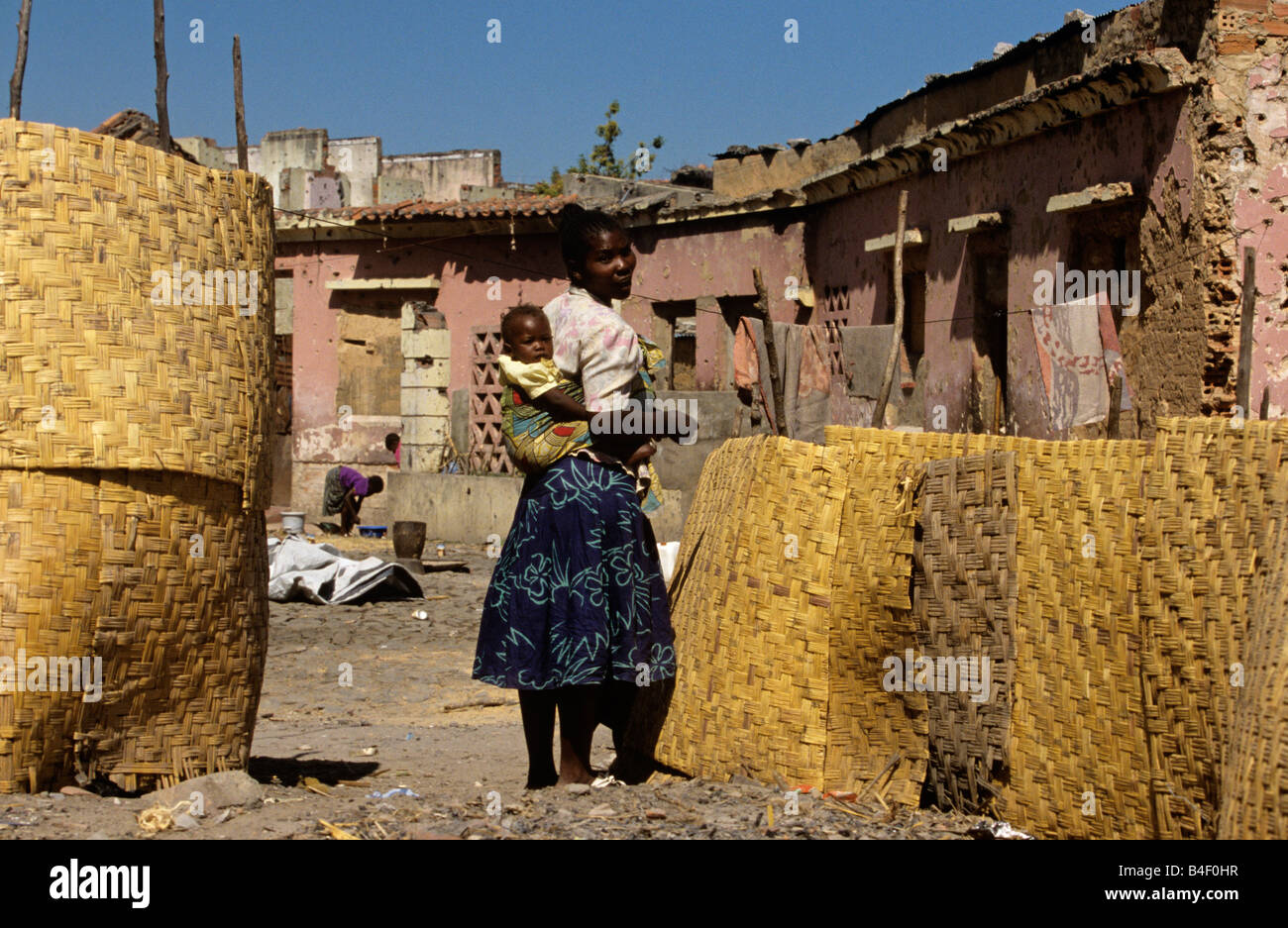 La madre e il Bambino accanto a Mat scherma e guerra-case danneggiate, Angola Foto Stock