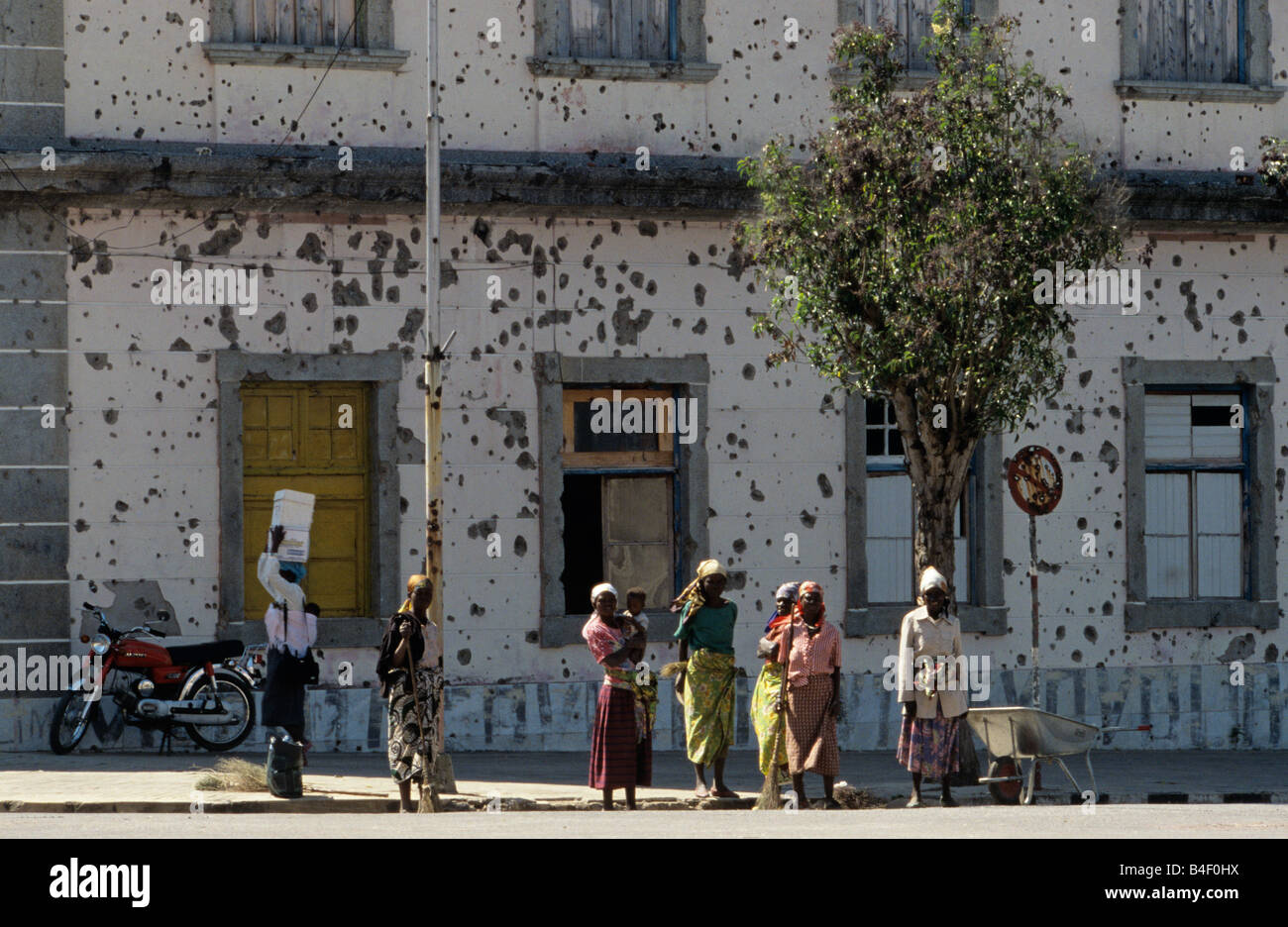 Le donne in piedi nella parte anteriore del bullet-riddled edificio in Angola Foto Stock