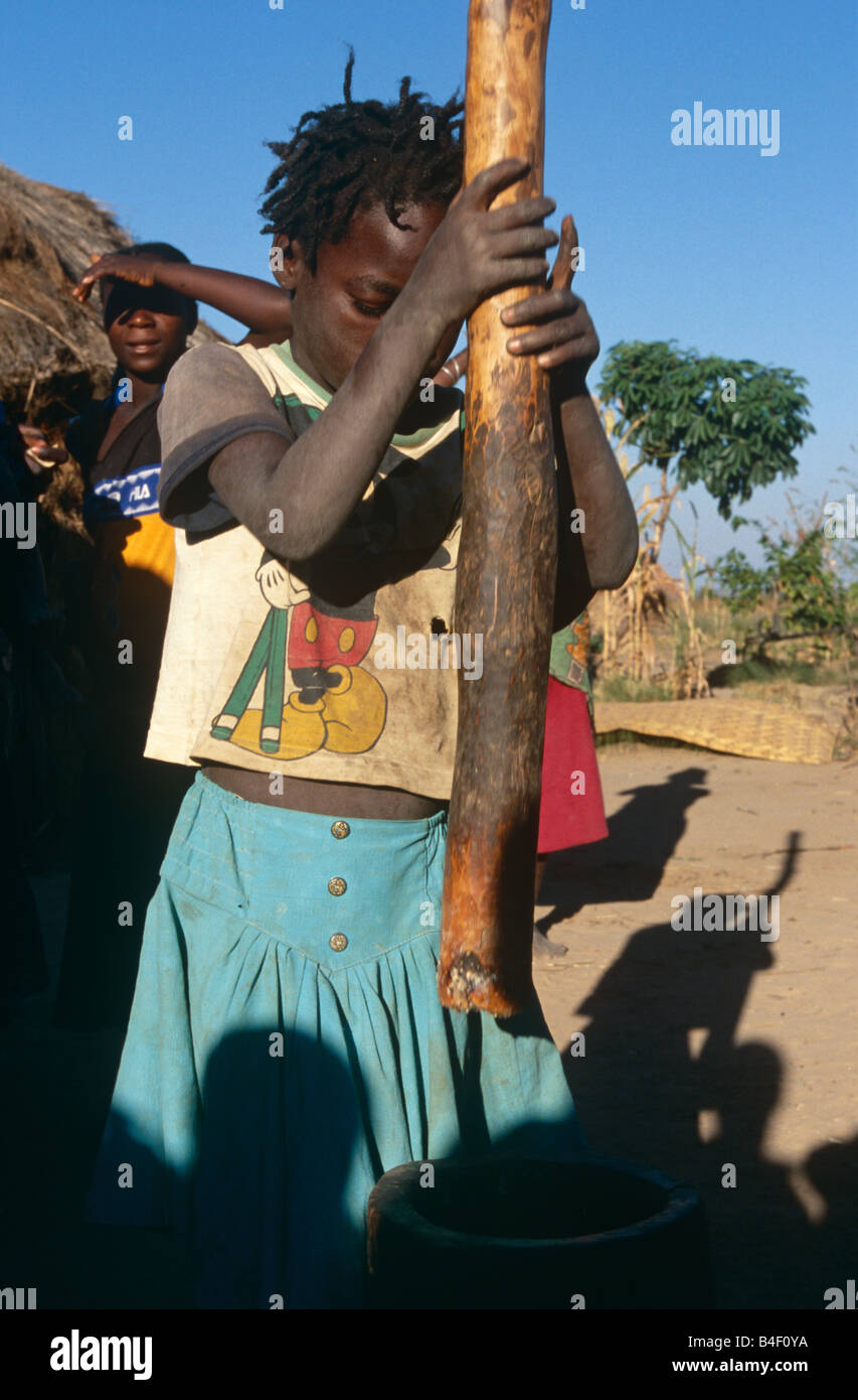 Spostata la donna a camp usando il pestello e mortaio per triturazione, Angola Foto Stock