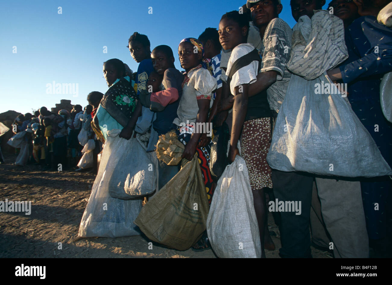 Gli sfollati coda per ricevere la distribuzione degli aiuti da ONG a cura di un accampamento in Angola. Foto Stock