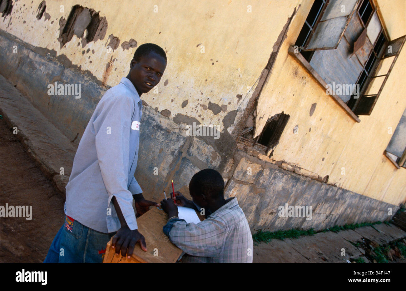 Gli uomini in una strada a devastate dalla guerra in Angola. Foto Stock