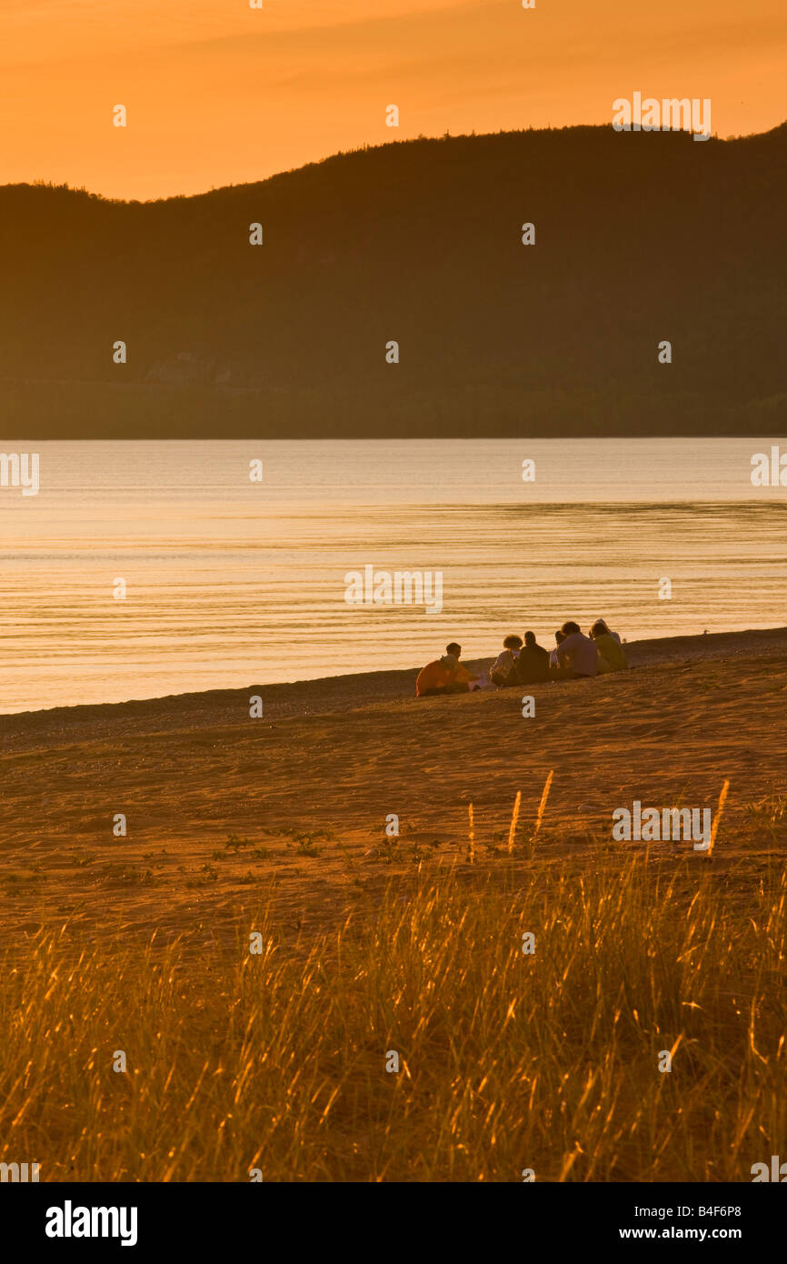 Gruppo di persone sedute sulla spiaggia nella baia di Agawa al tramonto, Lago Superiore, Lago Superior parco provinciale, Ontario, Canada. Foto Stock