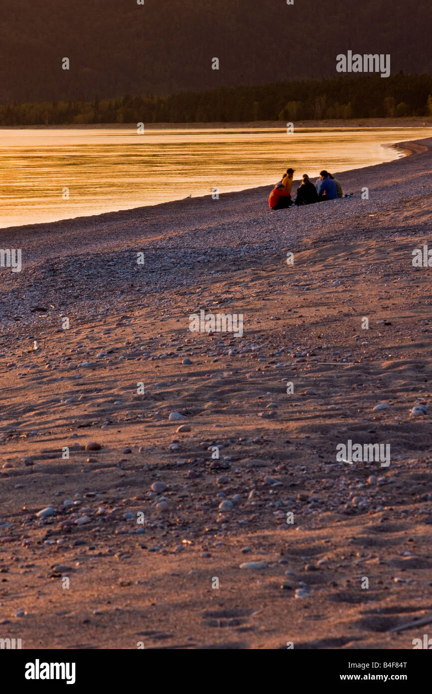 Gruppo di persone sedute sulla spiaggia nella baia di Agawa al tramonto, Lago Superiore, Lago Superior parco provinciale, Ontario, Canada. Foto Stock