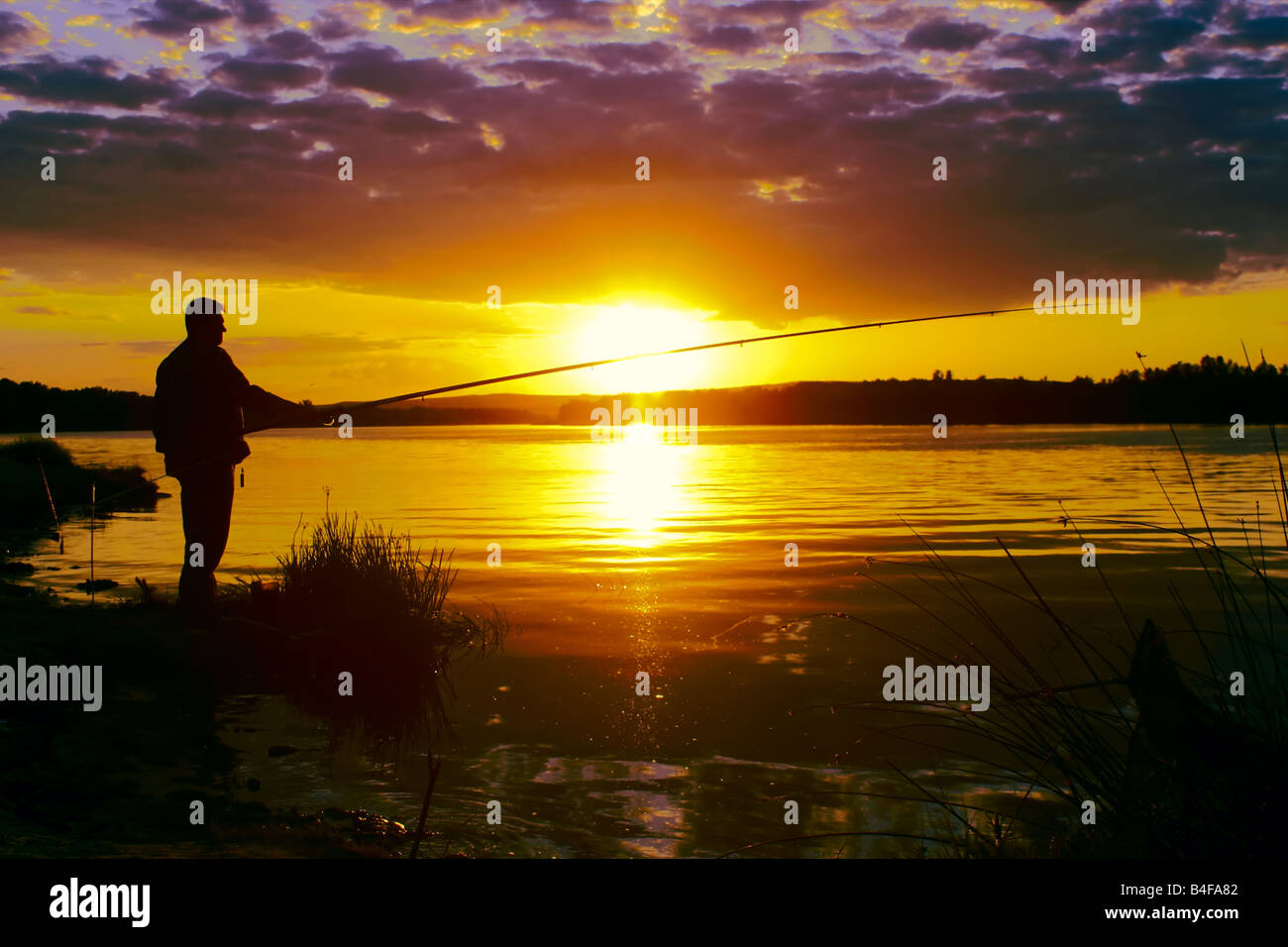 Un solo uomo sul tranquillo fiume sotto i raggi del sole di sera Foto Stock