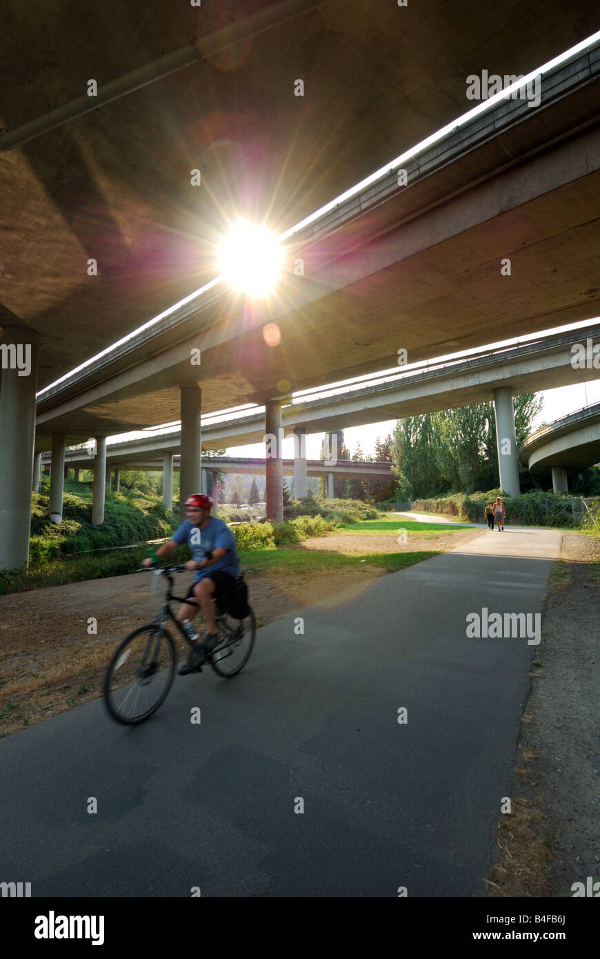 Un uomo che cavalca la sua bicicletta sotto I-405 lungo Bothell's Sammamish River Trail. Foto Stock