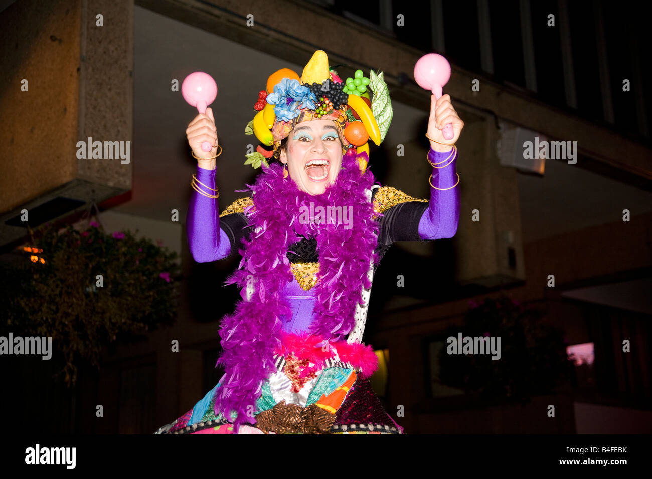 Un gioioso carnevale intrattenitore aiuta la folla divertirsi in una strada di carnevale. Foto Stock