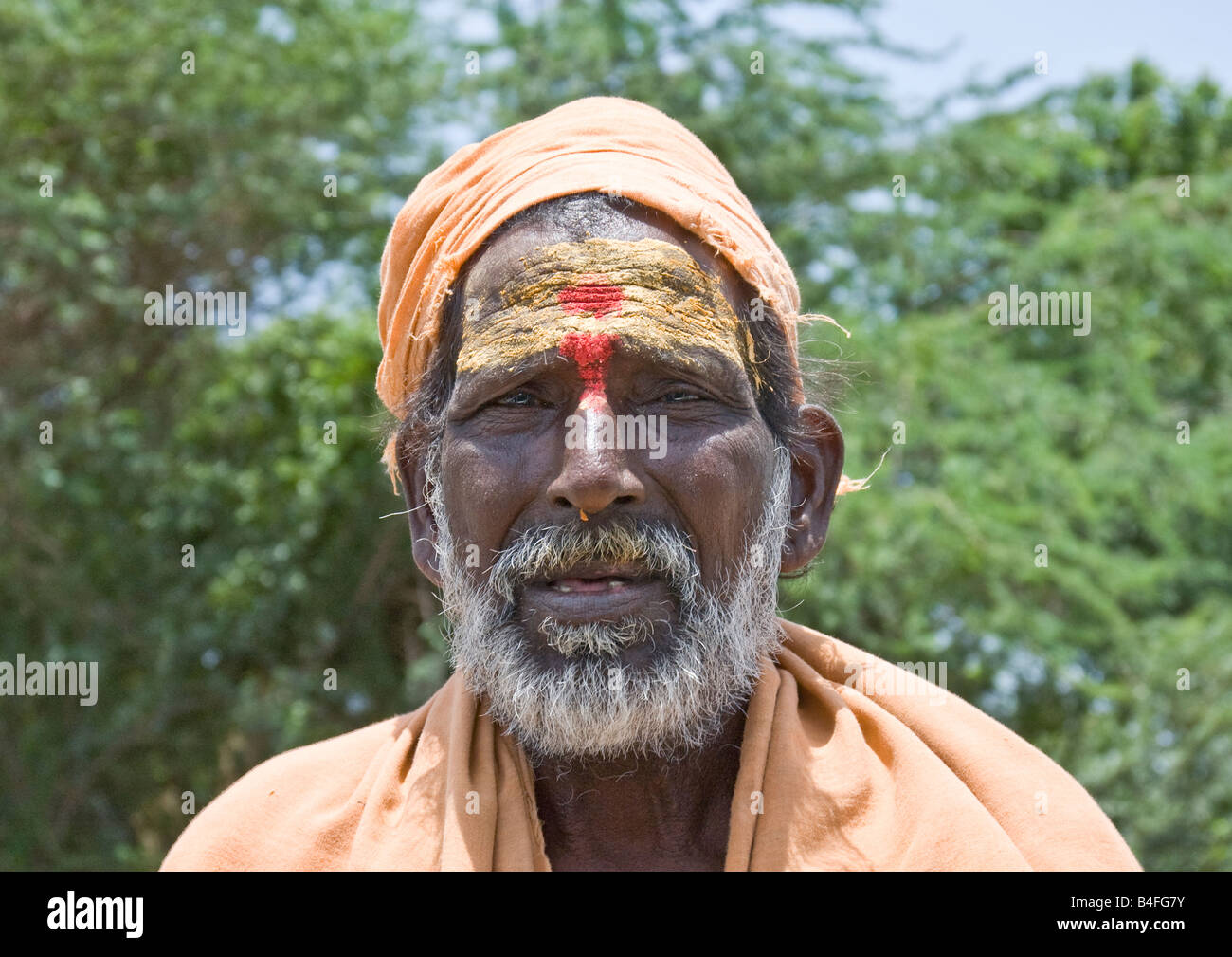 Un chiedendo sadhu indiano con barba bianca e abiti dello zafferano, l'icona di ricerca spirituale, con la richiesta di una donazione di denaro o cibo. Foto Stock