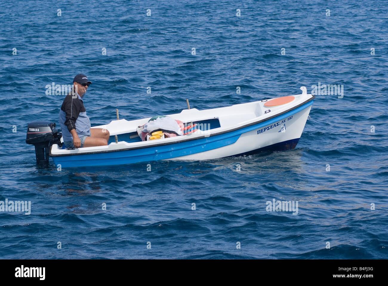 Un pescatore greco nella sua barca di fumare una sigaretta nel Mare Egeo nei pressi di Livadi città isola di Serifos Grecia Foto Stock