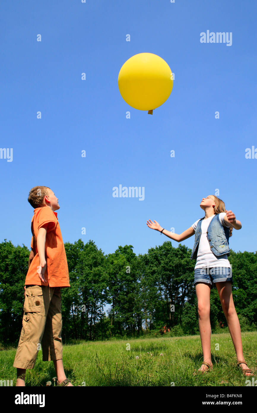 Un ragazzo e una ragazza che gioca con un grande palloncino giallo Foto Stock