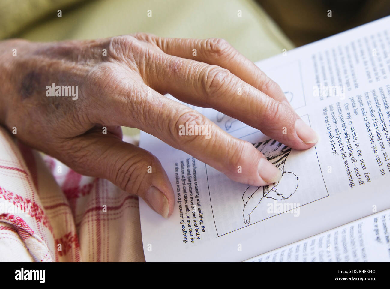 Vecchio mani artritiche sulla sommità del libro sui neonati Foto Stock