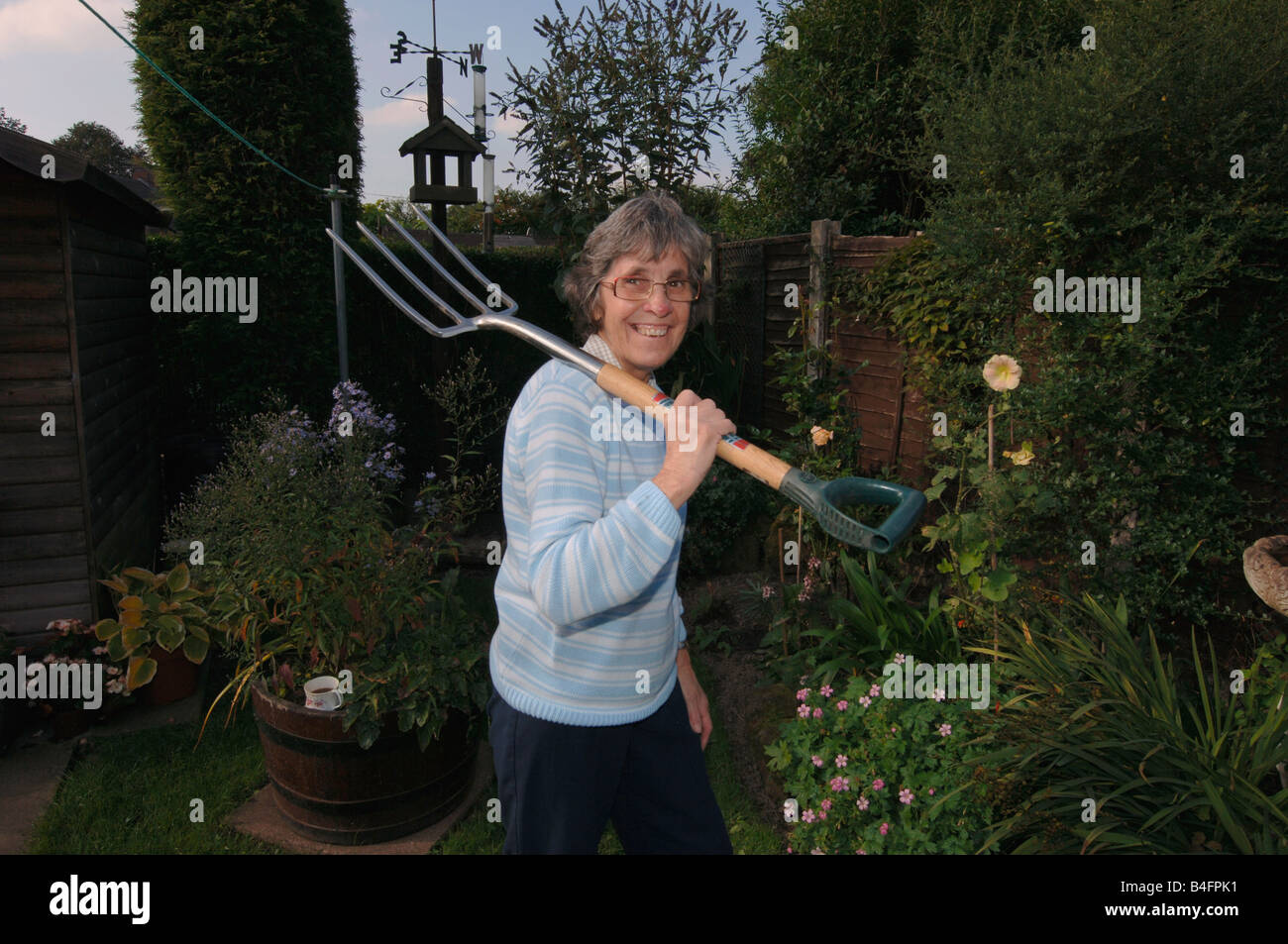 Una donna nel suo degli anni Settanta in posa con una forcella di giardino Foto Stock