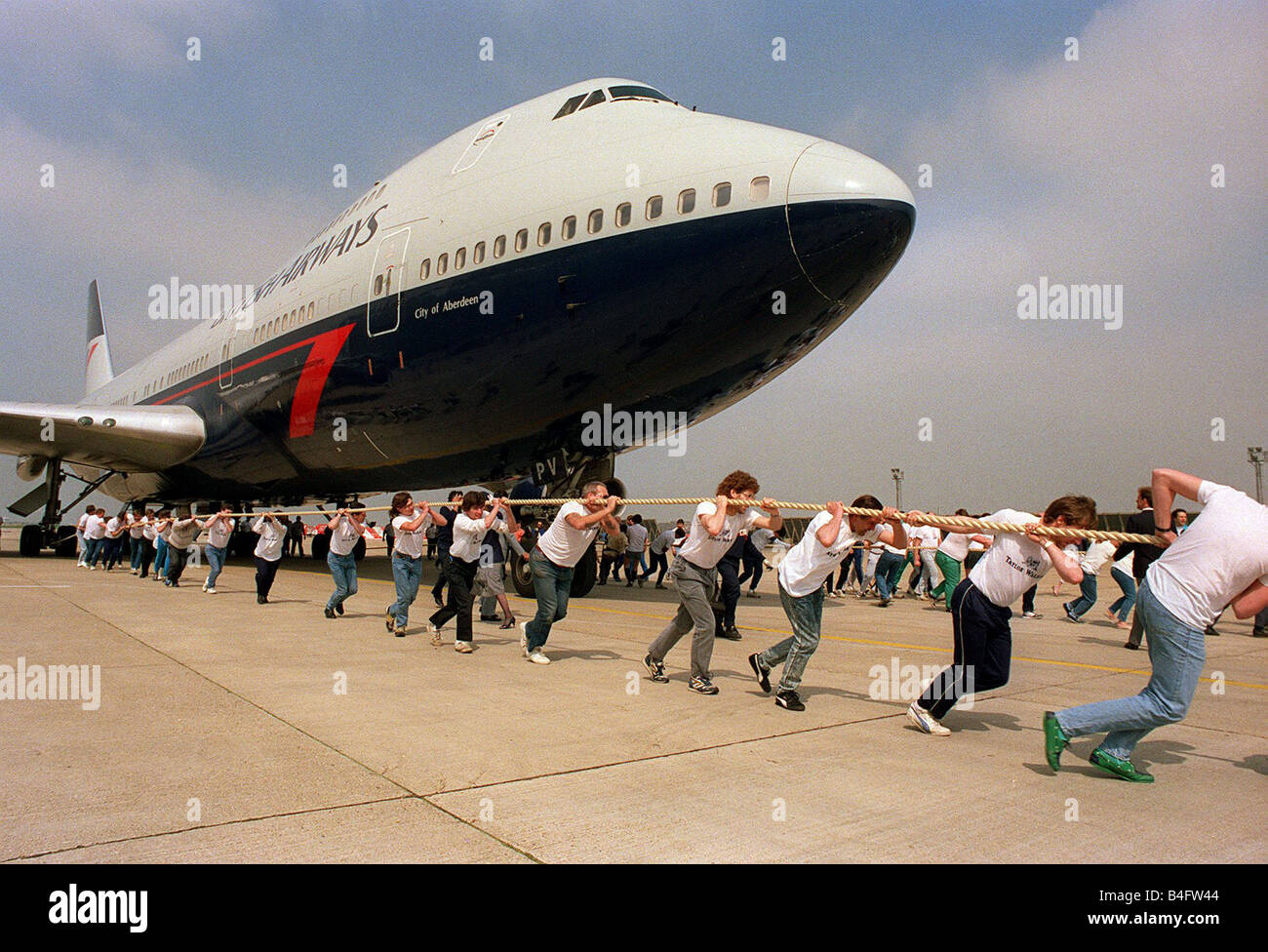 La carità aeromobile tirare un British Airways Boeing 747 Jumbo Jet viene tirato lungo la tarmac rimorchiatore di stile guerra all' Aeroporto di Heathrow 1988 Foto Stock