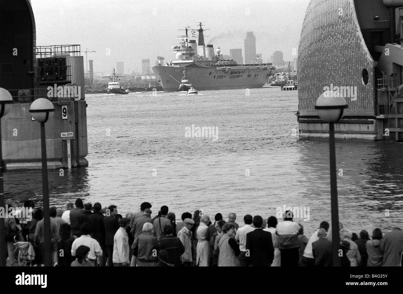 HMS Ark Royal Portaerei Giugno 1987 a Greenwich folla attendono l arrivo della Royal Navy portaerei Ark Royal presso la Thames Flood Barrier La Ark Royal visto qui trainato a valle del Tamigi da due tug imbarcazioni con una metropolitana Fiume scorta di polizia era stato in visita a Londra Giugno 1987 anni ottanta Foto Stock