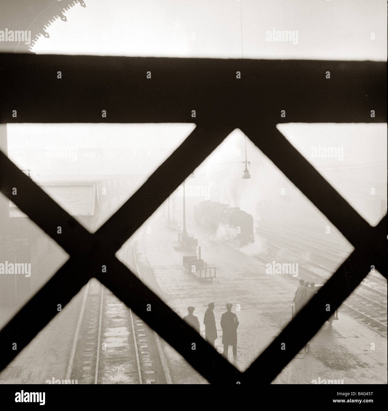 Dalla stazione di Liverpool Street London il tetto ad arco è archiviato con fumo di un treno a vapore come si tira nella stazione del 1950 circa Foto Stock
