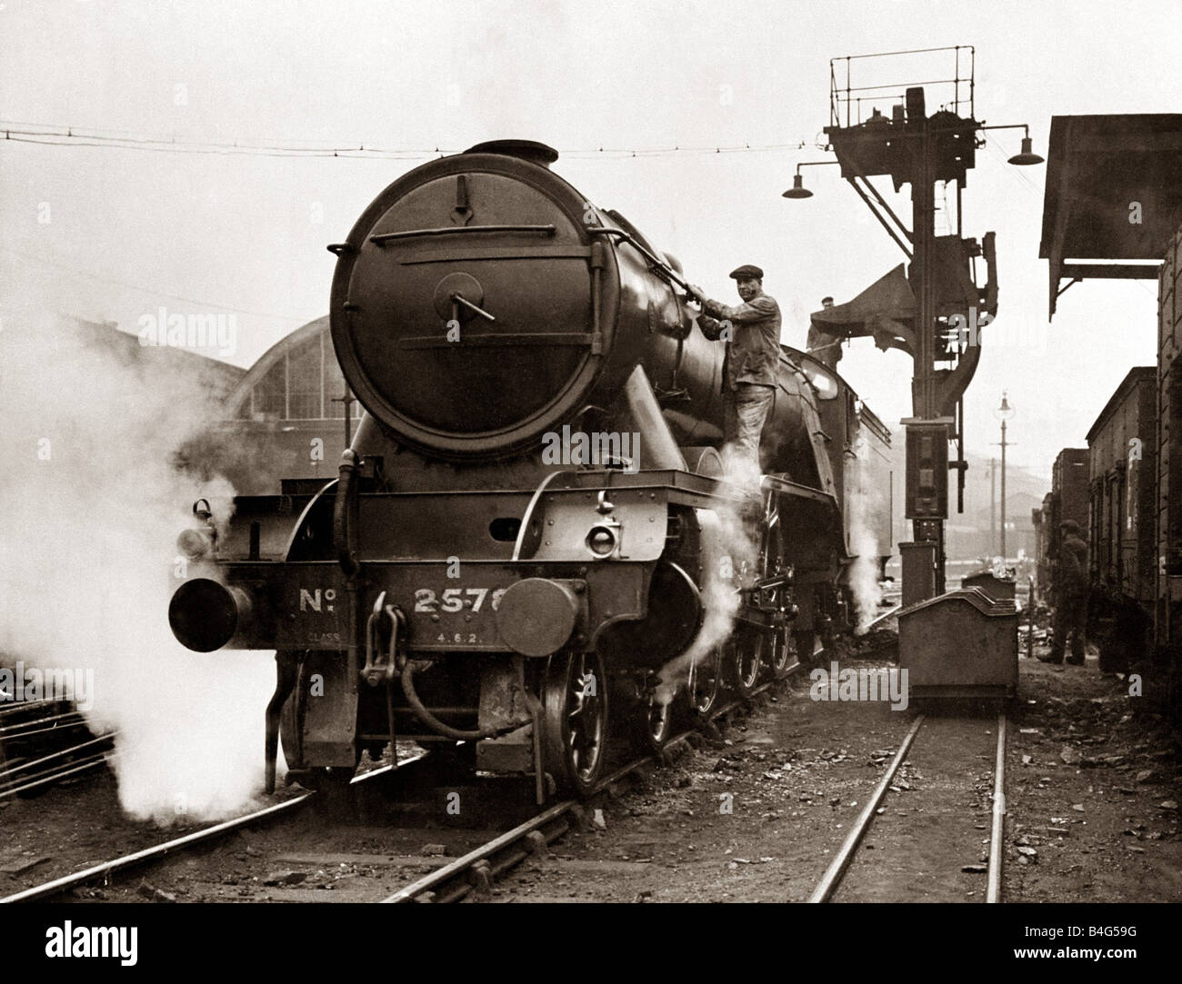 Rivestimento elettrico installazione e pozzetto di ispezione presso la stazione di Kings Cross mentre questa operazione avviene il conducente e il pompiere pulire la locomotiva Settembre 1929 Foto Stock