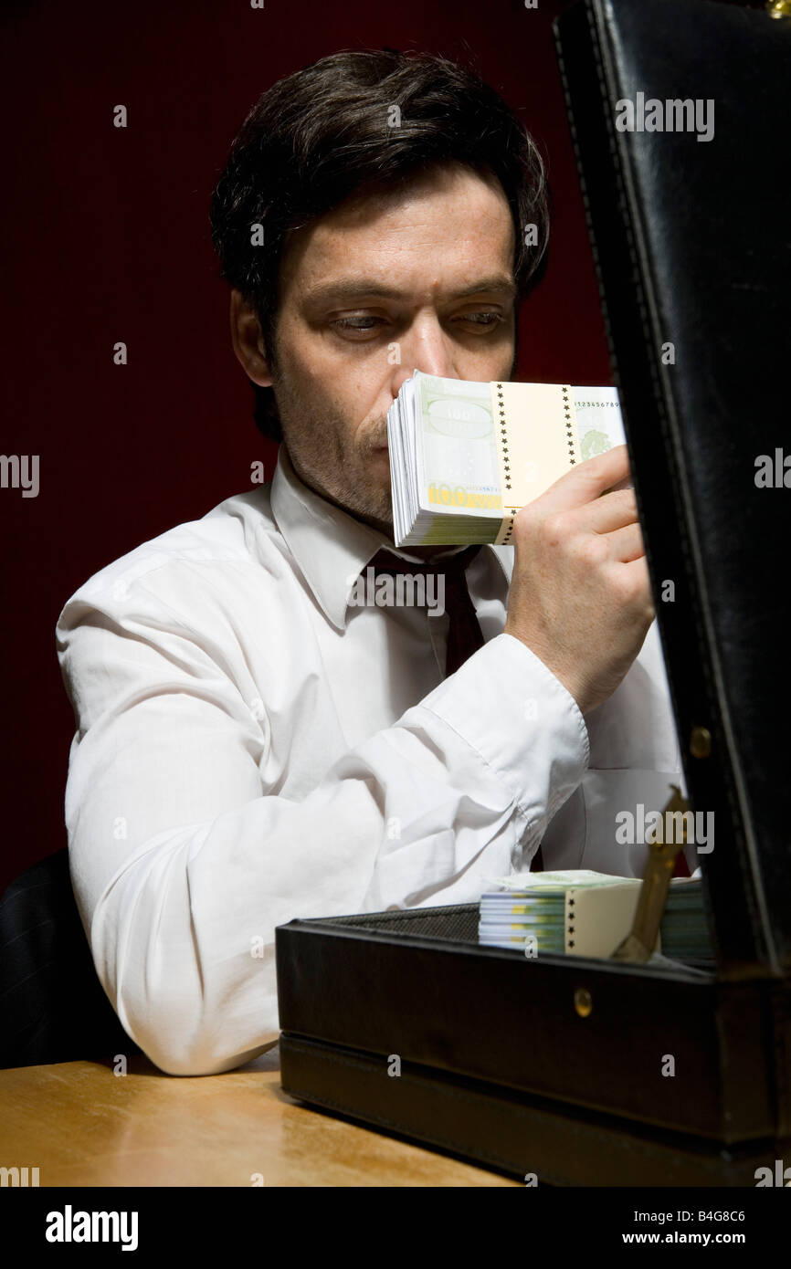 Un uomo odore di una pila di denaro Foto Stock