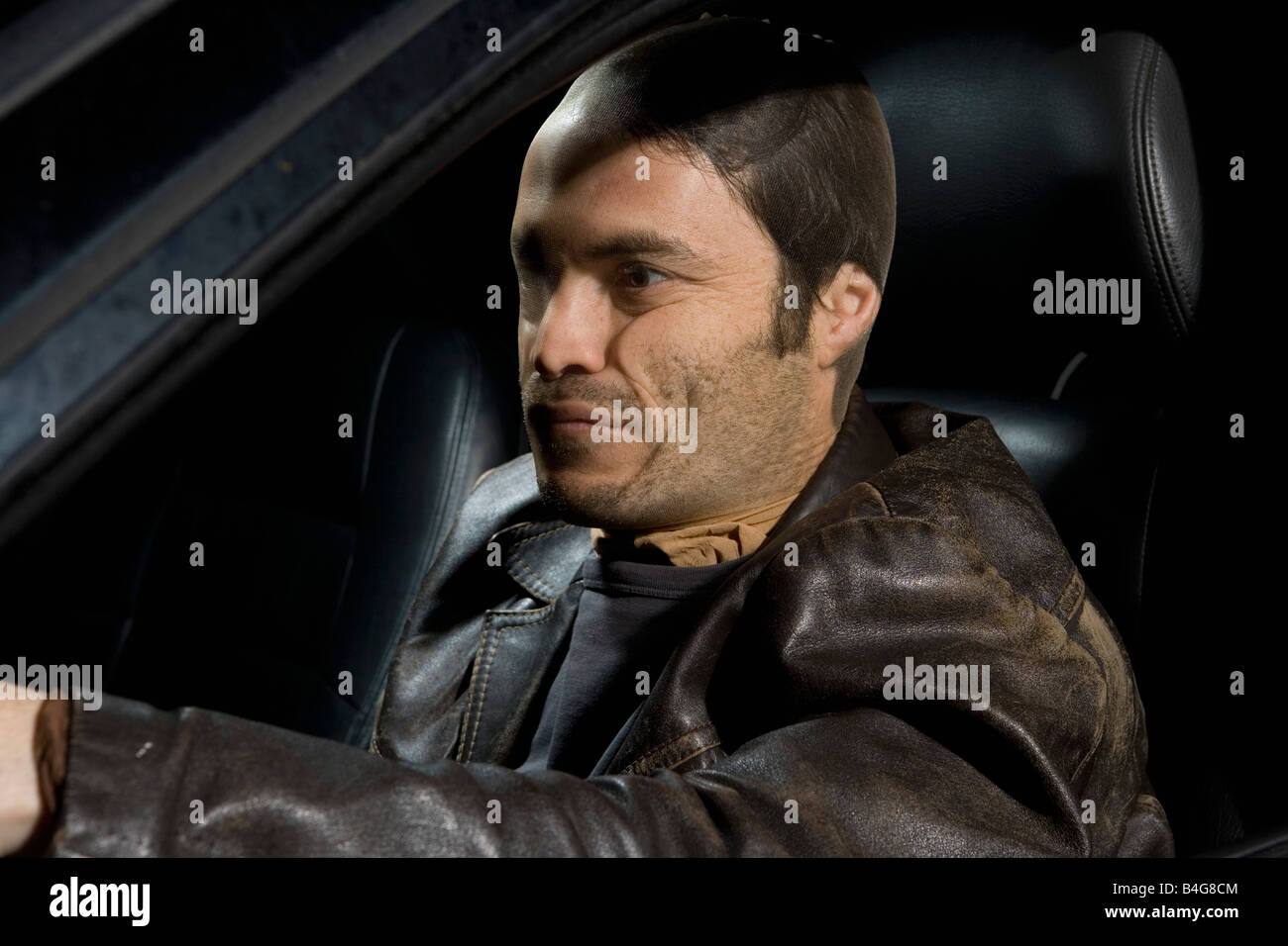 Un uomo con un nylon sul suo volto seduto in un auto Foto Stock