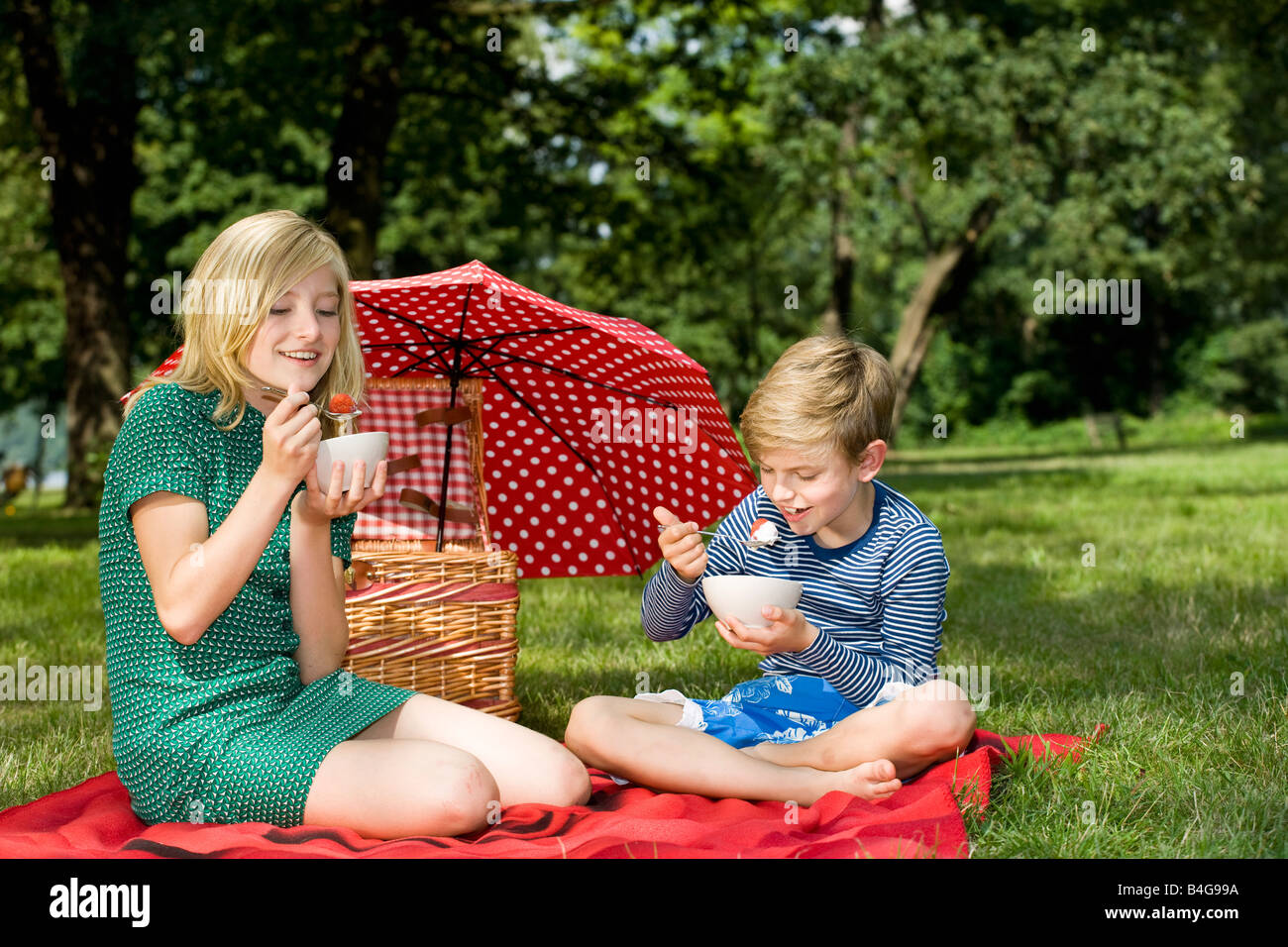 Due bambini di mangiare fragole e yogurt a un picnic Foto Stock