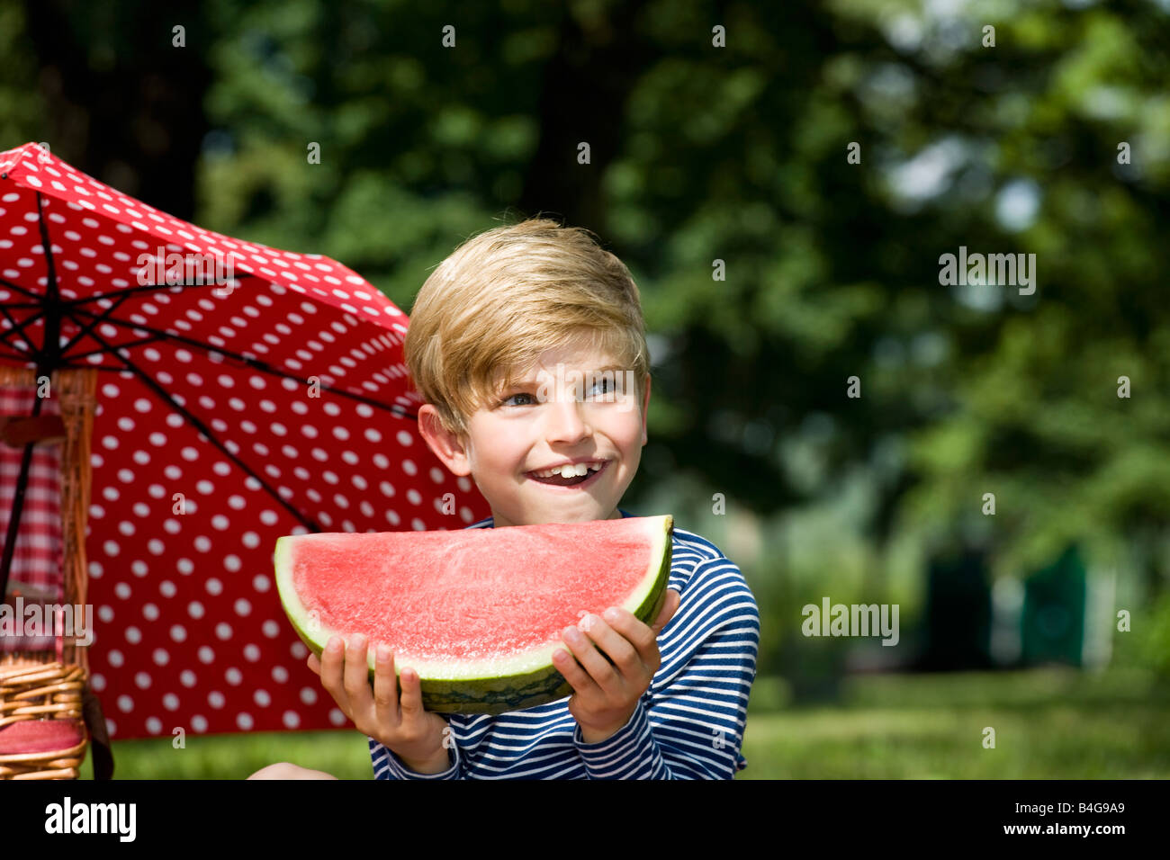 Un giovane ragazzo in possesso di una fetta di cocomero Foto Stock
